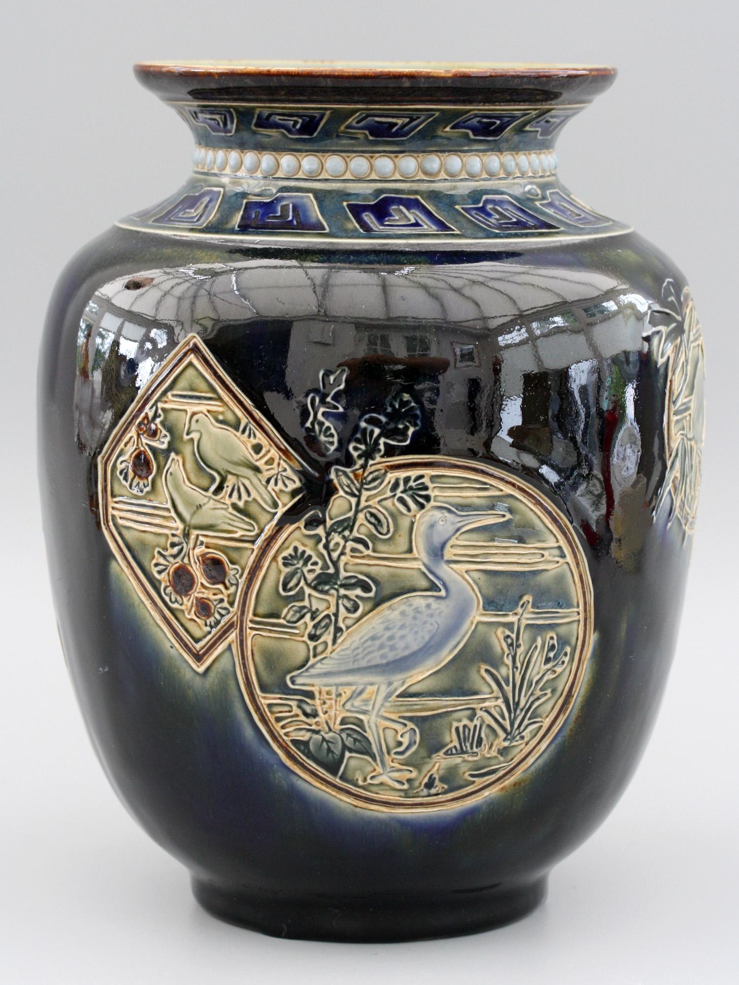 A rare and stunning Doulton Lambeth art pottery vase decorated with Japanese style panel designs containing birds and fish by Edward Dunn and John Broad and dated 1883. The stylish stoneware vase stands on a narrow rounded foot and is of large
