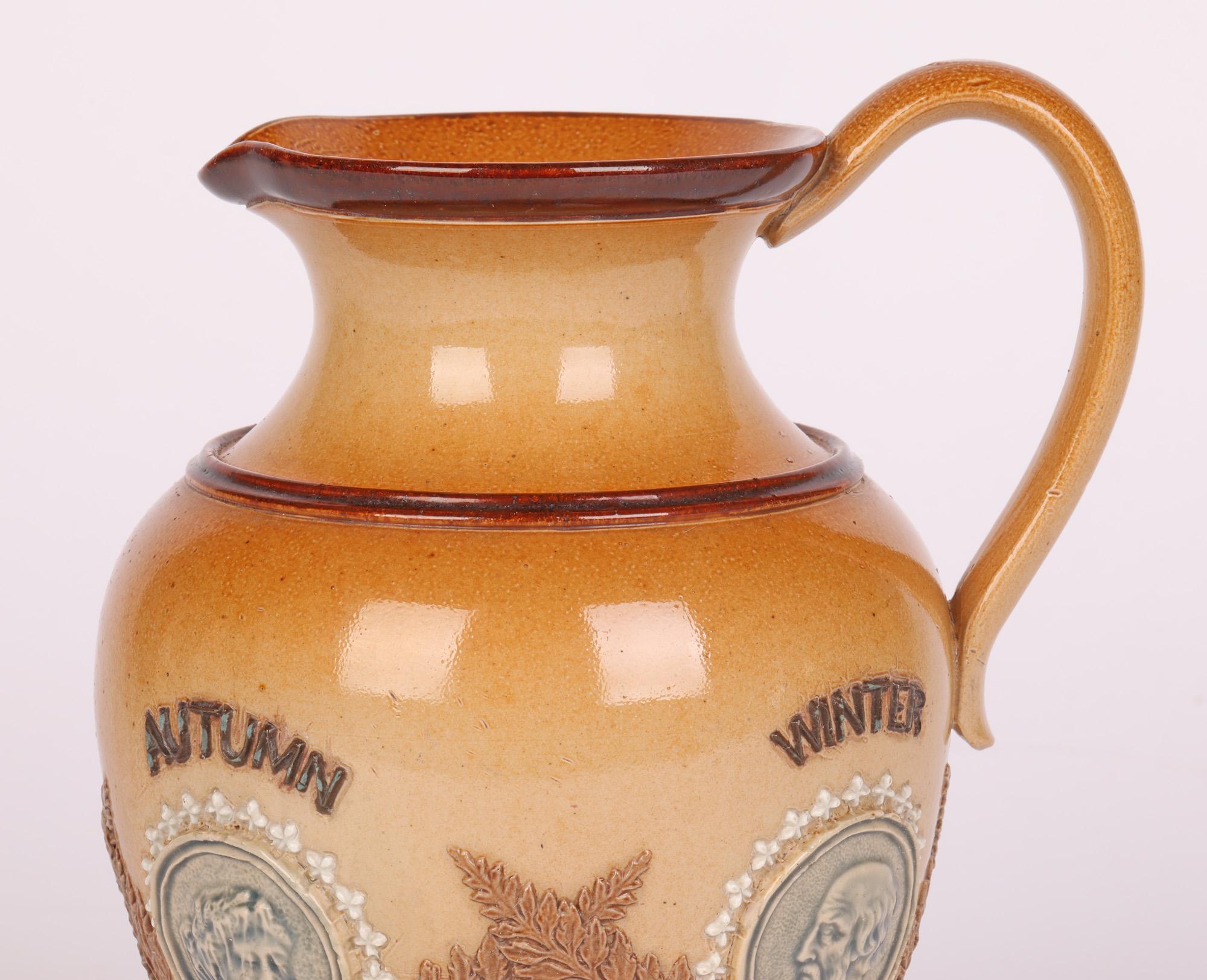 An unusual Doulton Lambeth jug decorated with figural medallions depicting the four seasons by Clara Baker and dated 1884. The stoneware jug is of rounded bulbous form standing on a narrow round foot, a pinched neck and wide rim with pouring spout.