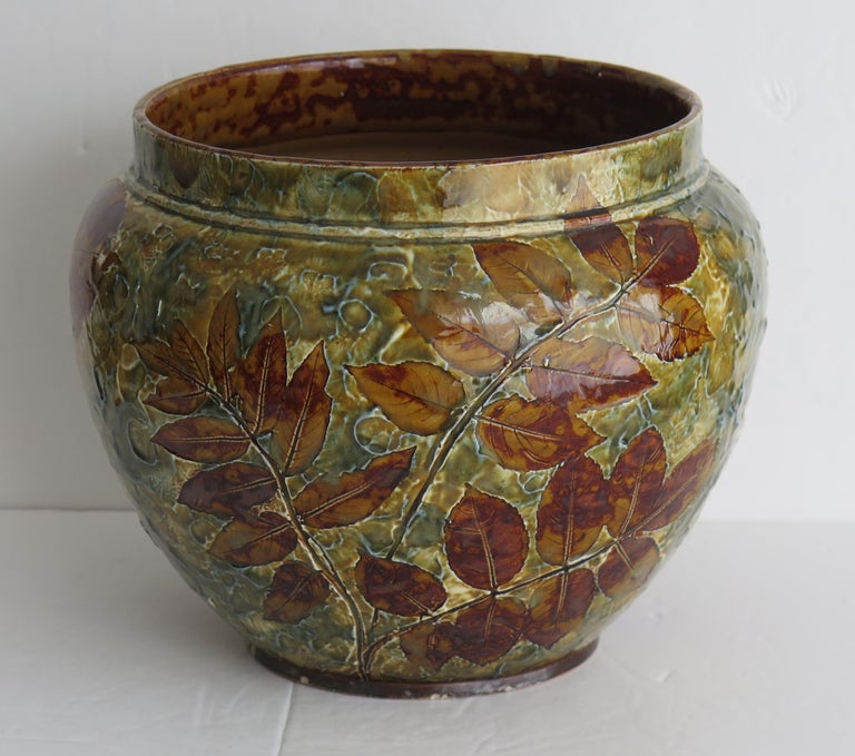 This is a very good stoneware Jardiniere , made by Doulton Lambeth, dating to Circa 1890.

The decoration has an applied moulded floral decoration which is hand enamelled, all in the Art Nouveau / Arts and Crafts style 

The piece is fully