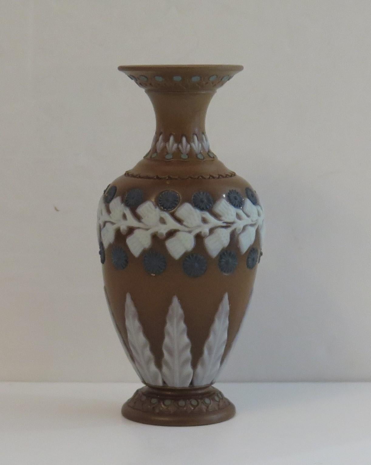 This is a very good small stoneware Vase by Doulton Lambeth silicon range, dating to 1861 to 1873.

The decoration has an applied moulded floral decoration in blue and white over a brown body, Art Nouveau in style 

The vase is fully marked to