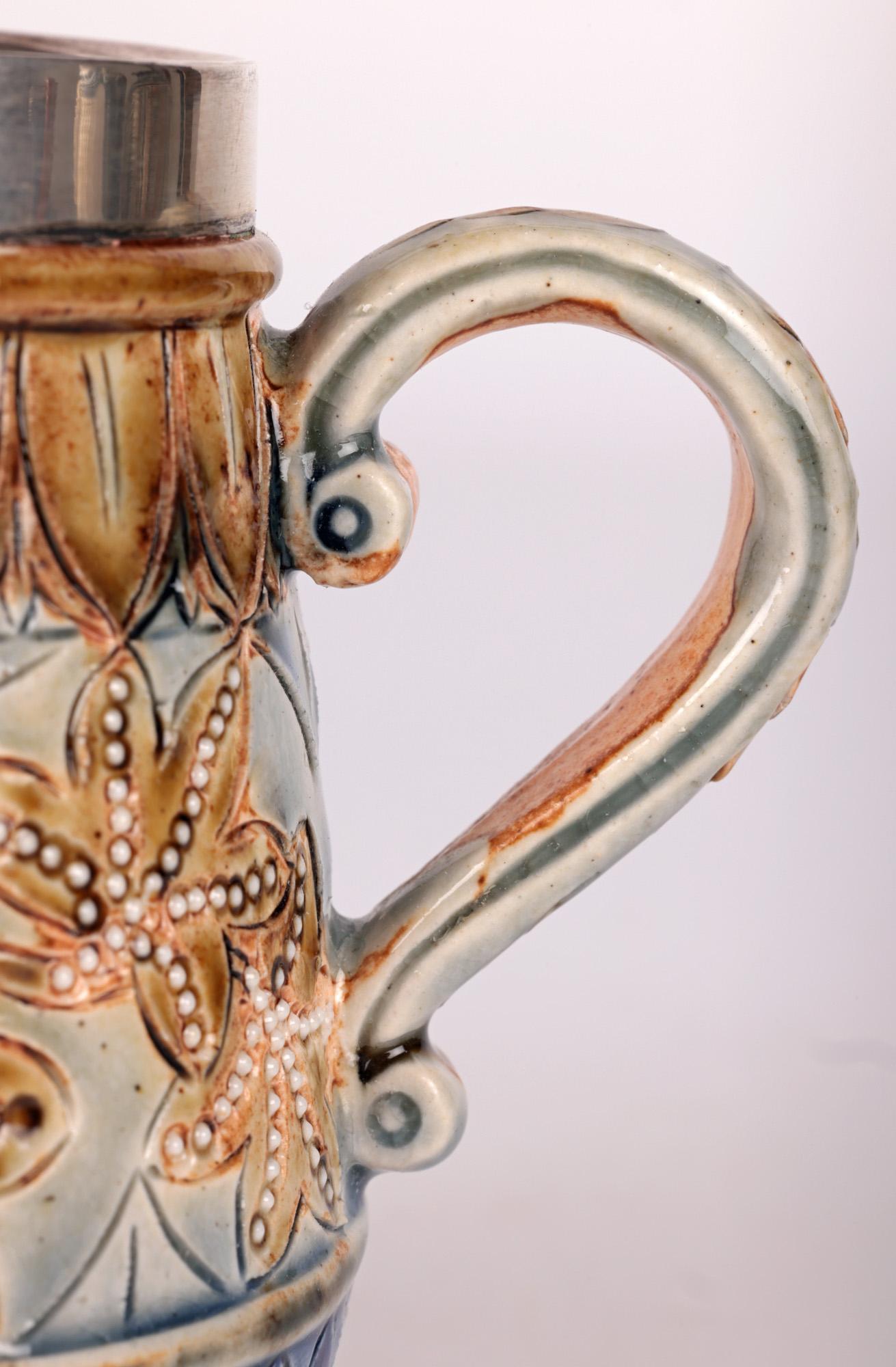 A stunning Doulton Lambeth stoneware silver mounted leaf design jug and early work by renowned designer and decorator Frances E Lee and dated 1877. The jug is finely made standing raised on a narrow round foot with a round beaker shaped body with