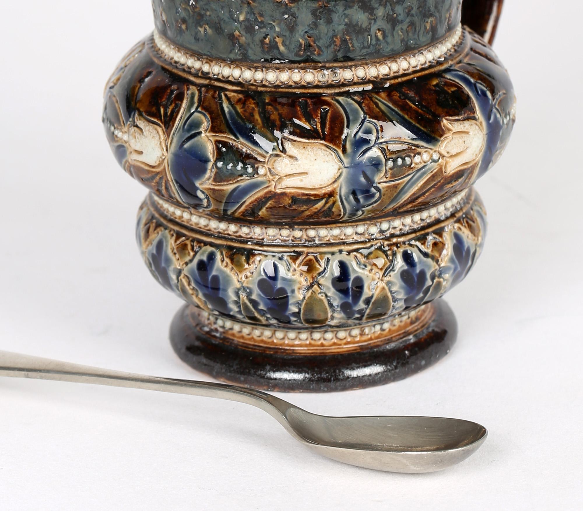 A fine and large Doulton Lambeth art pottery mustard pot with silver plated hinged cover by Emily Partington and dated 1880. The pot is of rounded shape with a loop handle applied to one side and stands on a narrow rounded pedestal foot with the