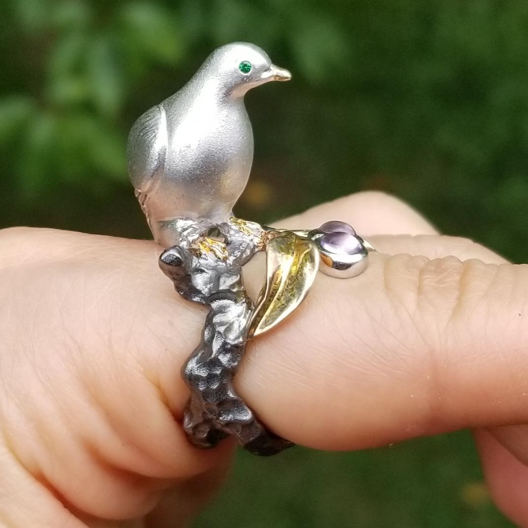 A symbol of peace, love, and harmony, the dove perches atop the finger, looking out for and protecting the wearer.
Her sparkling green favorite eyes represent life and nature.
Luminous pale violet cabochon amethysts represent plums from the fruit