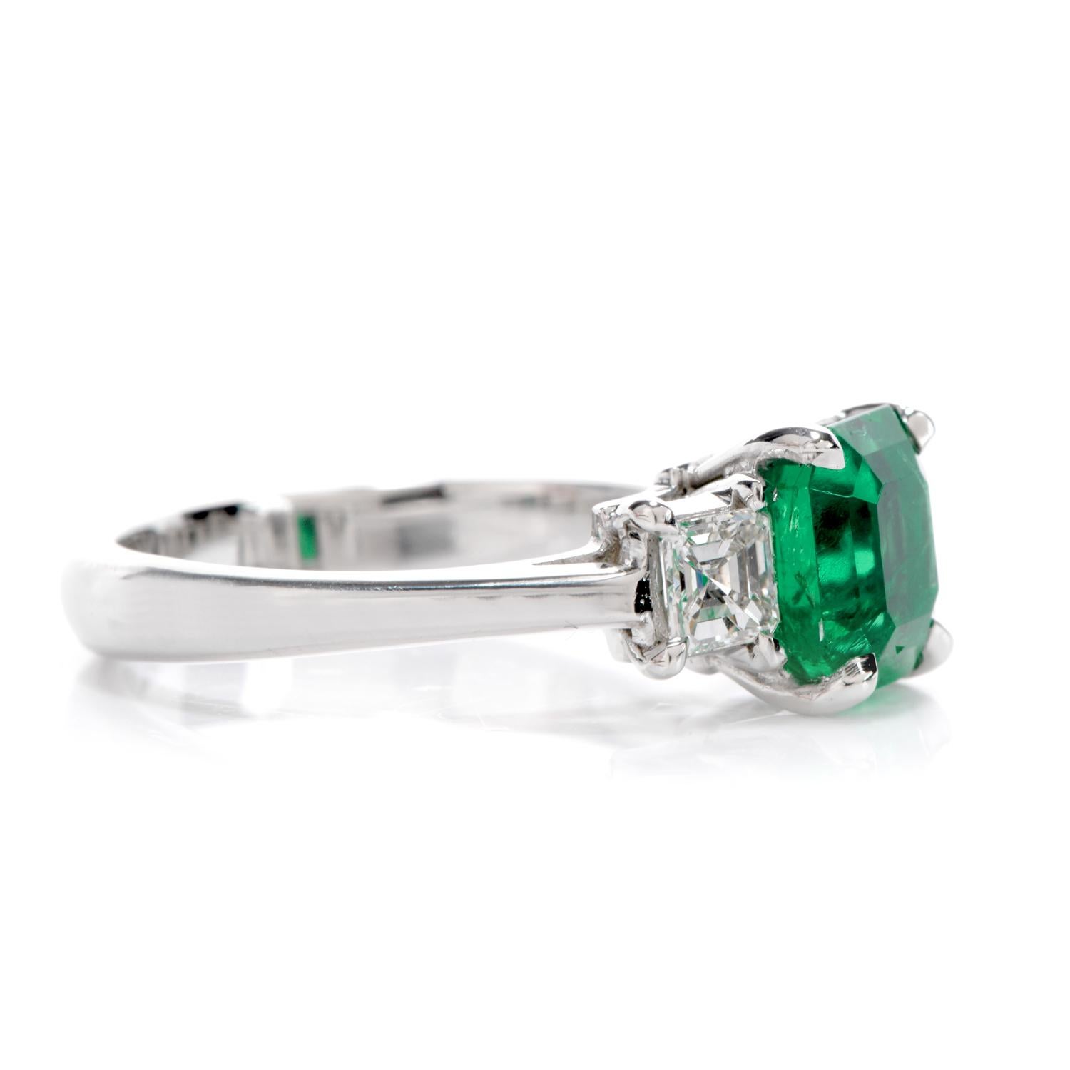 Let this glowing Colombian Emerald Platinum ring steal your breath away with its striking hue! 
This 1.41 carat center stone is accompanied by two crisp Asscher cut diamonds totaling 0.50 carats, E-F Color VVS clarity.. 
The classic three-stone