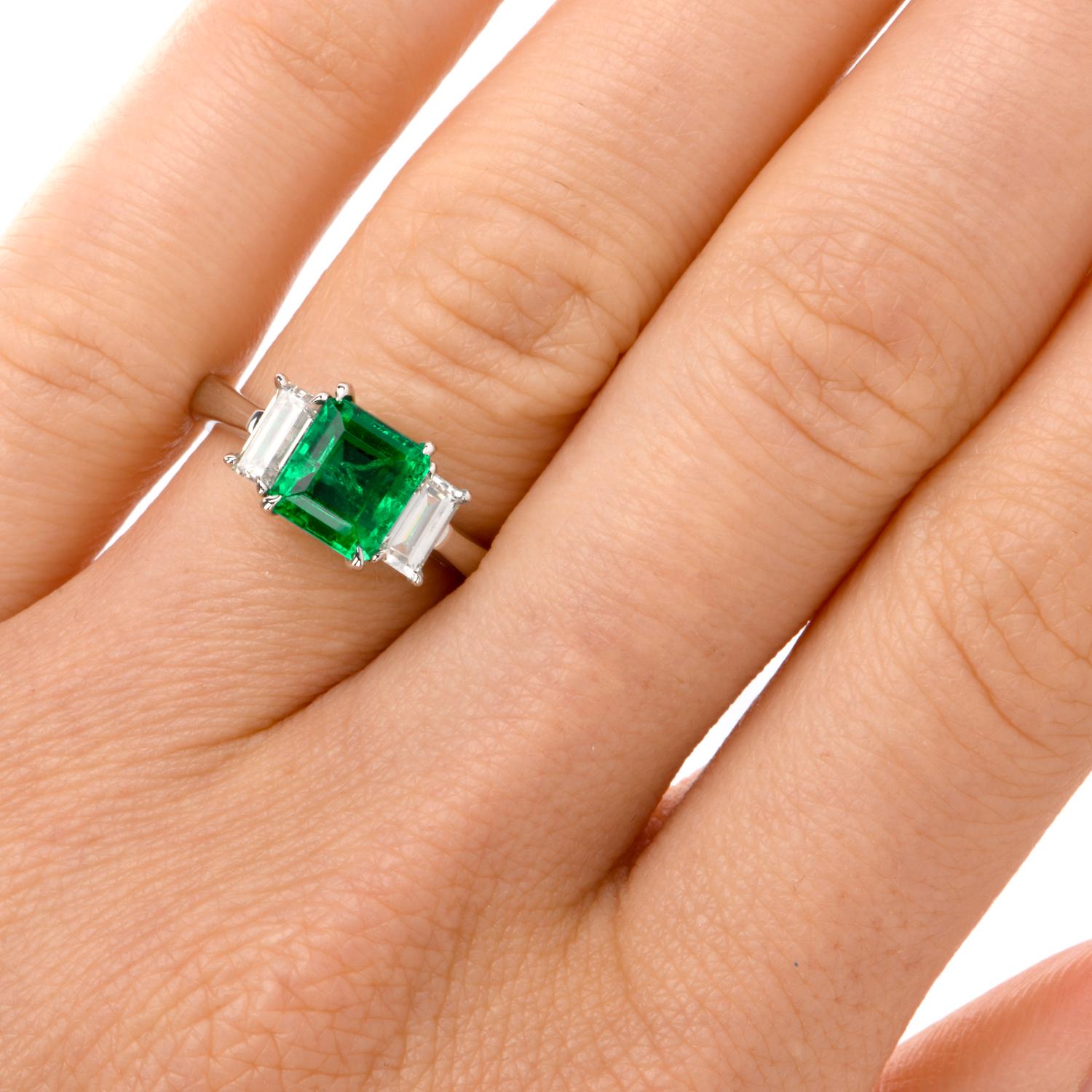 This classic three stone ring is crafted in solid platinum. It exposes at the center avery fine genuine Colombian Emerald, weighing 1.65 cts measuring approx: 7.27 x 6.62 x 4.65mm; and flanked by a pair of genuine baguette diamonds collectively