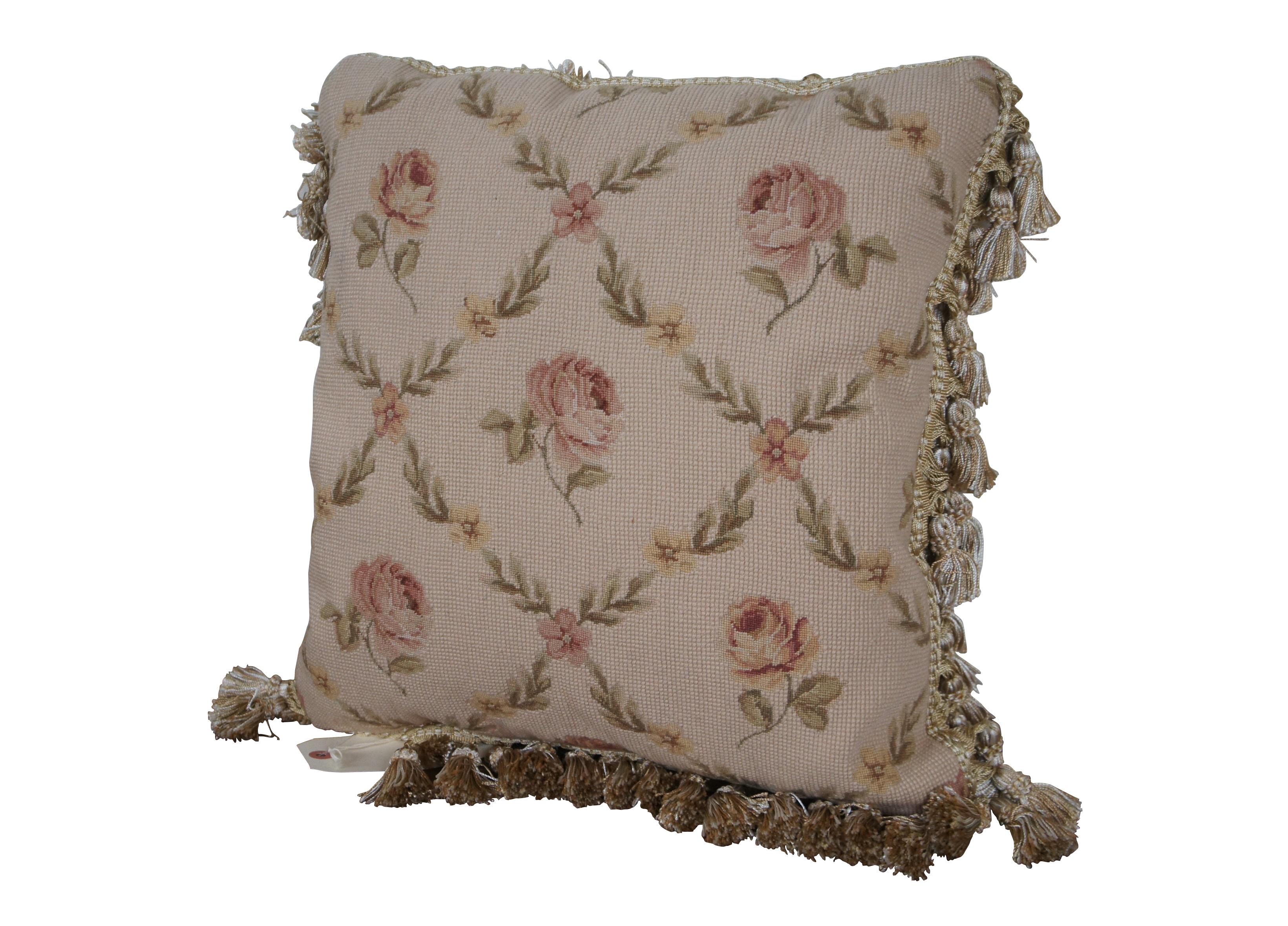 5 Available - 20th century square needlepoint throw pillow, hand embroidered with a pattern of pink roses, divided by criss crossing lines of pink and yellow flowers and leaves, on a beige background. Cream and gold tassel trim. Beige velour back