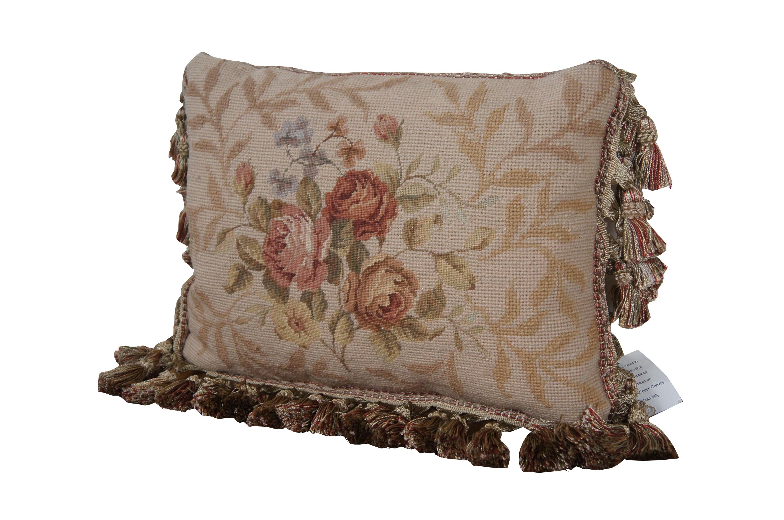 20th century rectangular needlepoint lumbar / throw pillow, hand embroidered in wool with a bouquet of pink, rust, yellow, and blue roses / flowers on a backdrop of beige leaves. Beige and red tassel trim. Beige velour back with zipper closure. Down