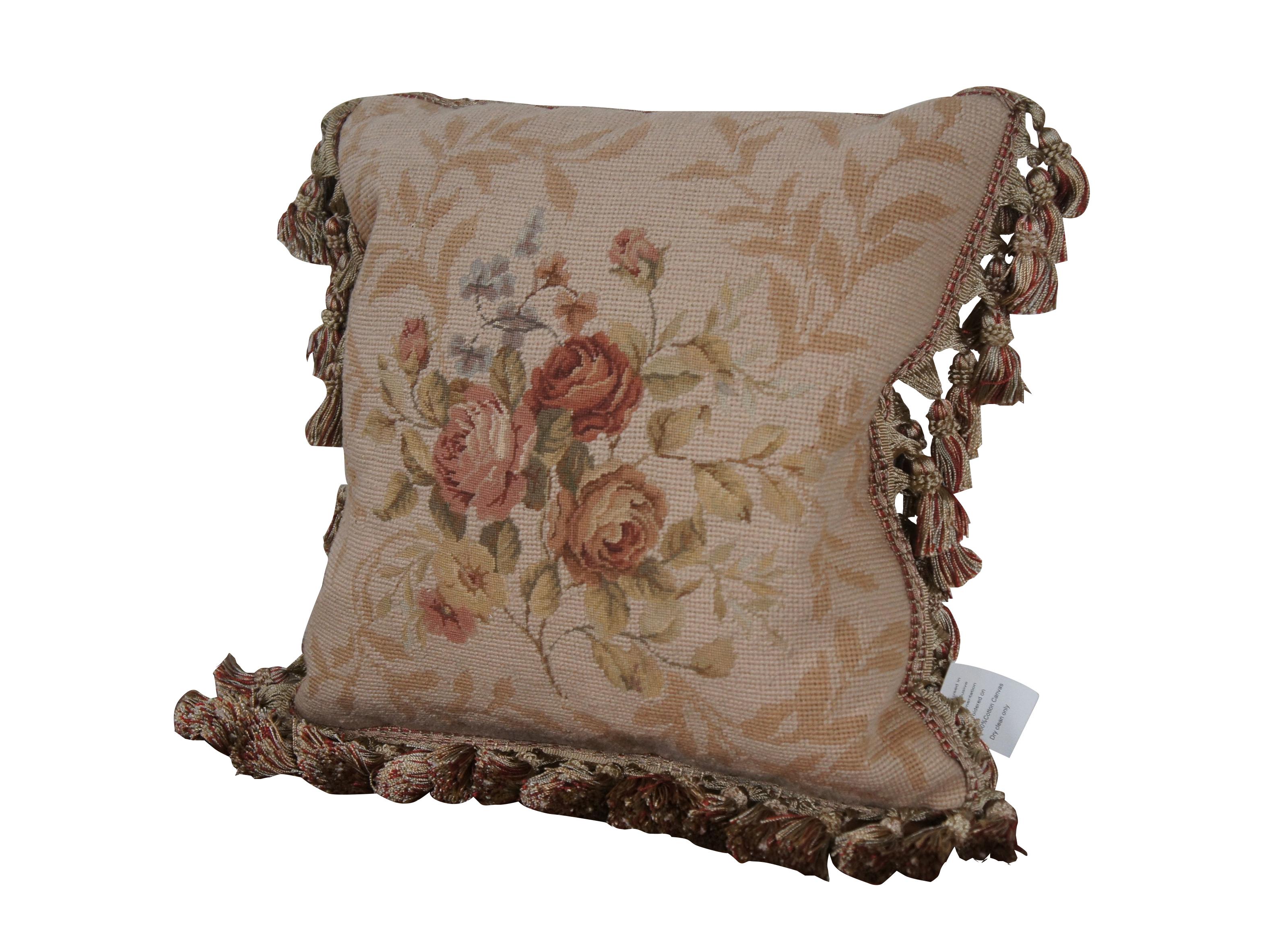 2 Available - 20th century square needlepoint throw pillow, hand embroidered in wool with a bouquet of pink, rust, yellow, and blue roses / flowers on a backdrop of beige leaves. Beige and red tassel trim. Beige velour back with zipper closure. Down