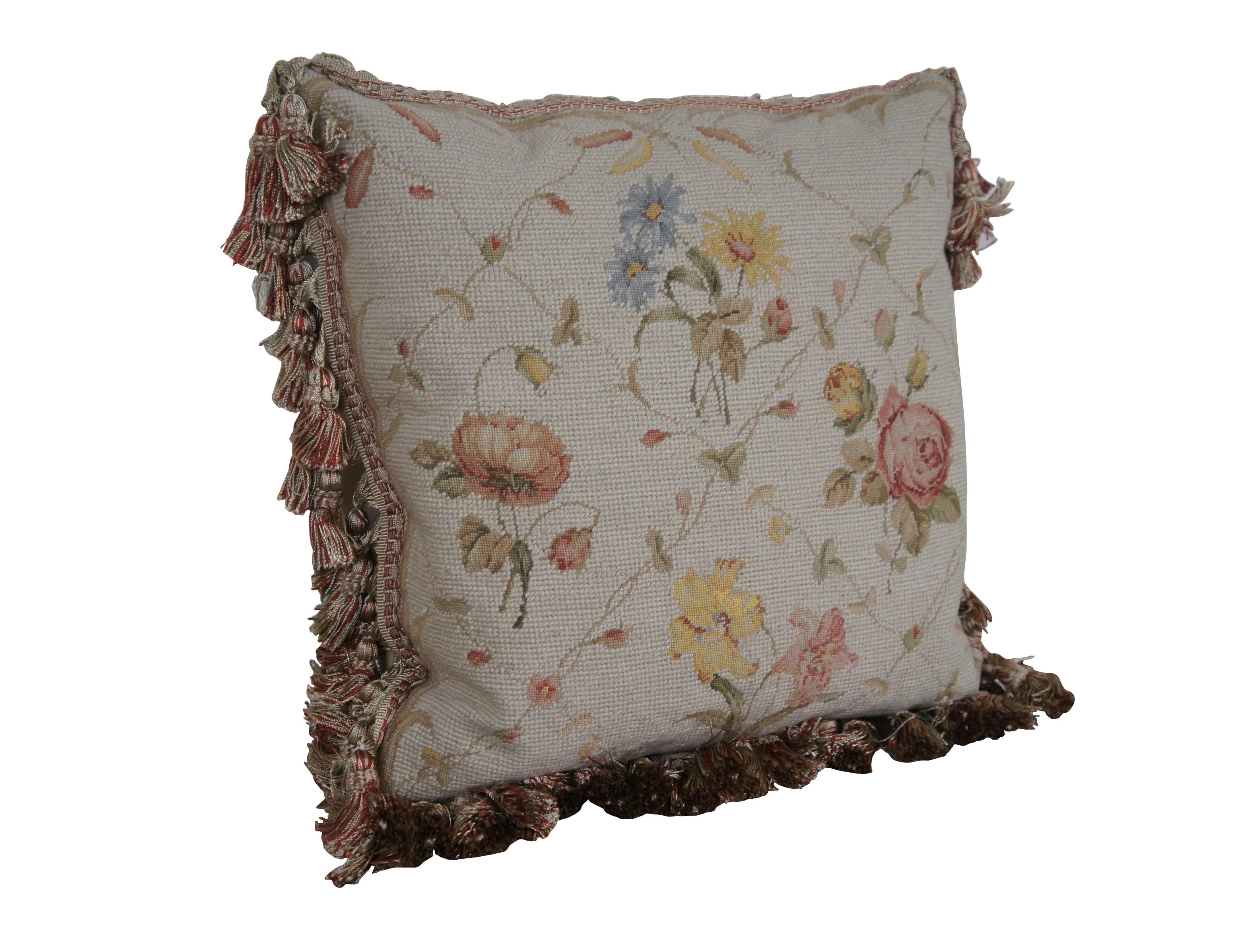 20th century square needlepoint throw pillow, hand embroidered with roses, lilies and daisies in pink, blue, and yellow, divided with criss crossing vines. Rust / rose, gold, and beige tassel trim. Beige velour back with zipper closure. Down