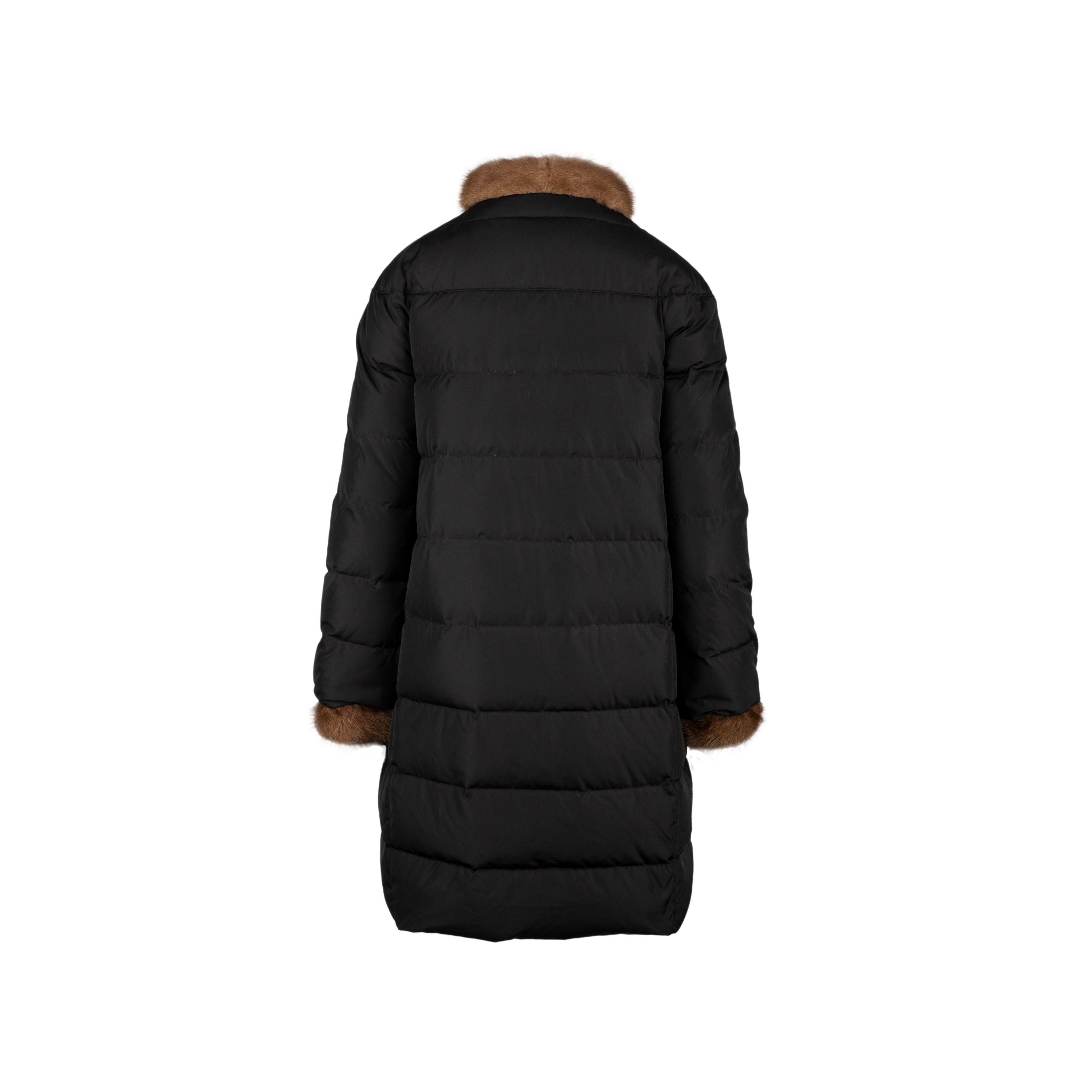Chaqueta de plumón Moncler negra con cuello y puños de visón marrón, diseño acampanado, bolsillos delanteros y doble botonadura frontal. Longitud total:91; Medida mangas:70; Busto:50