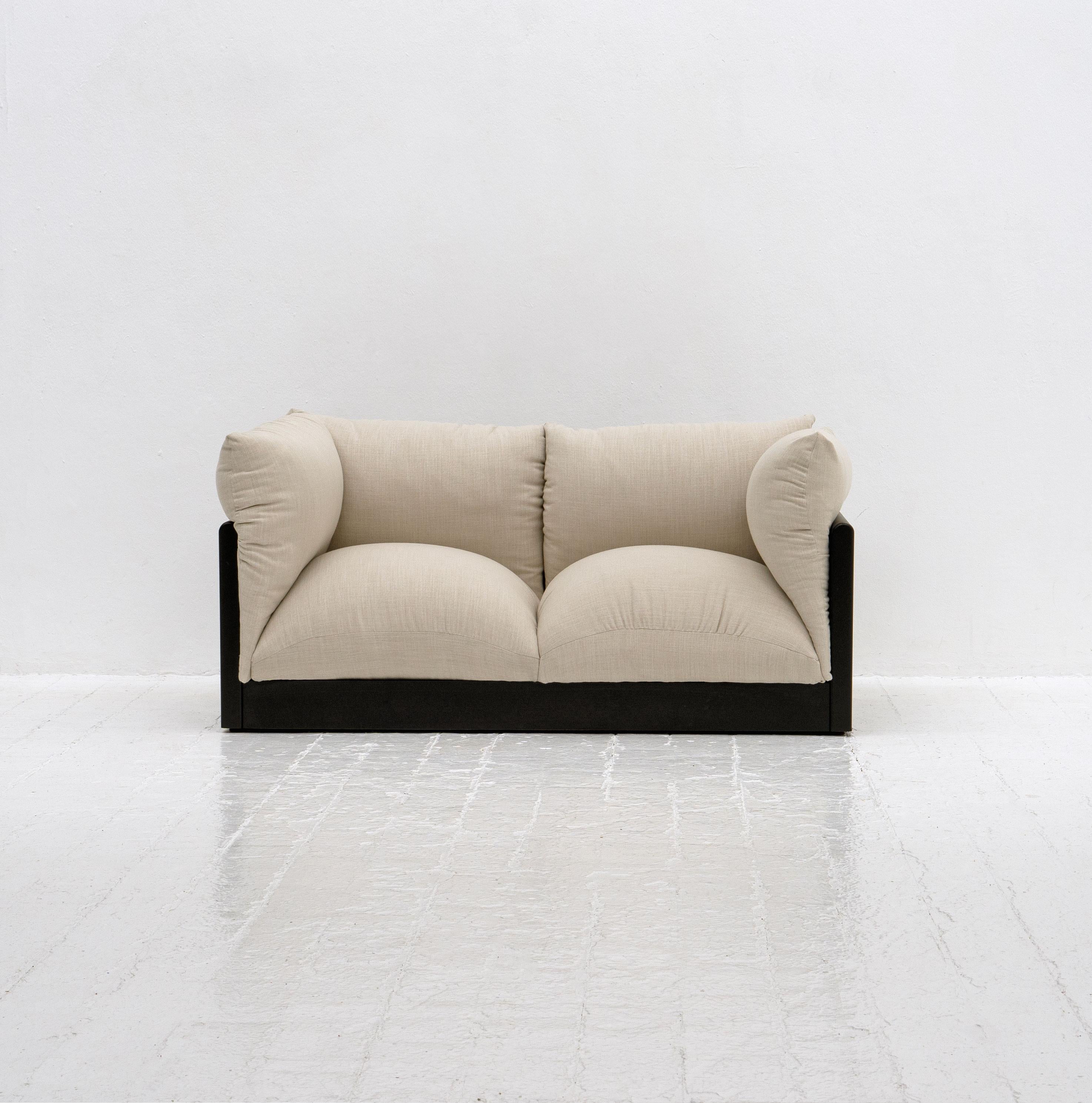 A 'Down' sofa designed by Italian architect and designer Carlo Bartoli and produced by Rossi Di Albizzate in 1972. Composed from lacquered wood, statement overfilled cushions and recently upholstered in a thick off-white cotton fabric. 

Dimensions