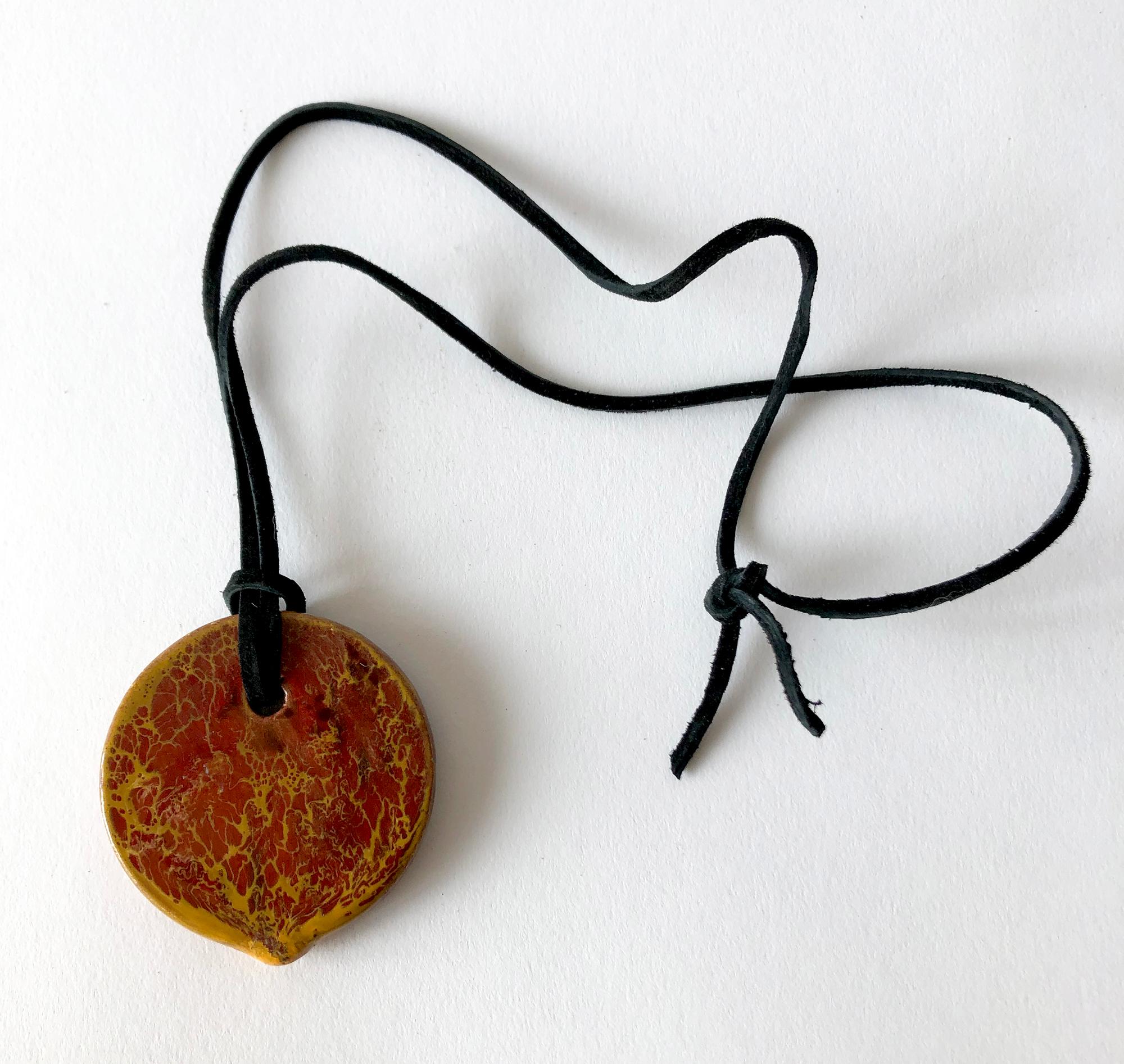 Flattened ceramic bead on suede strap by Doyle Lane of Los Angeles, California. Bead measures 2 3/8