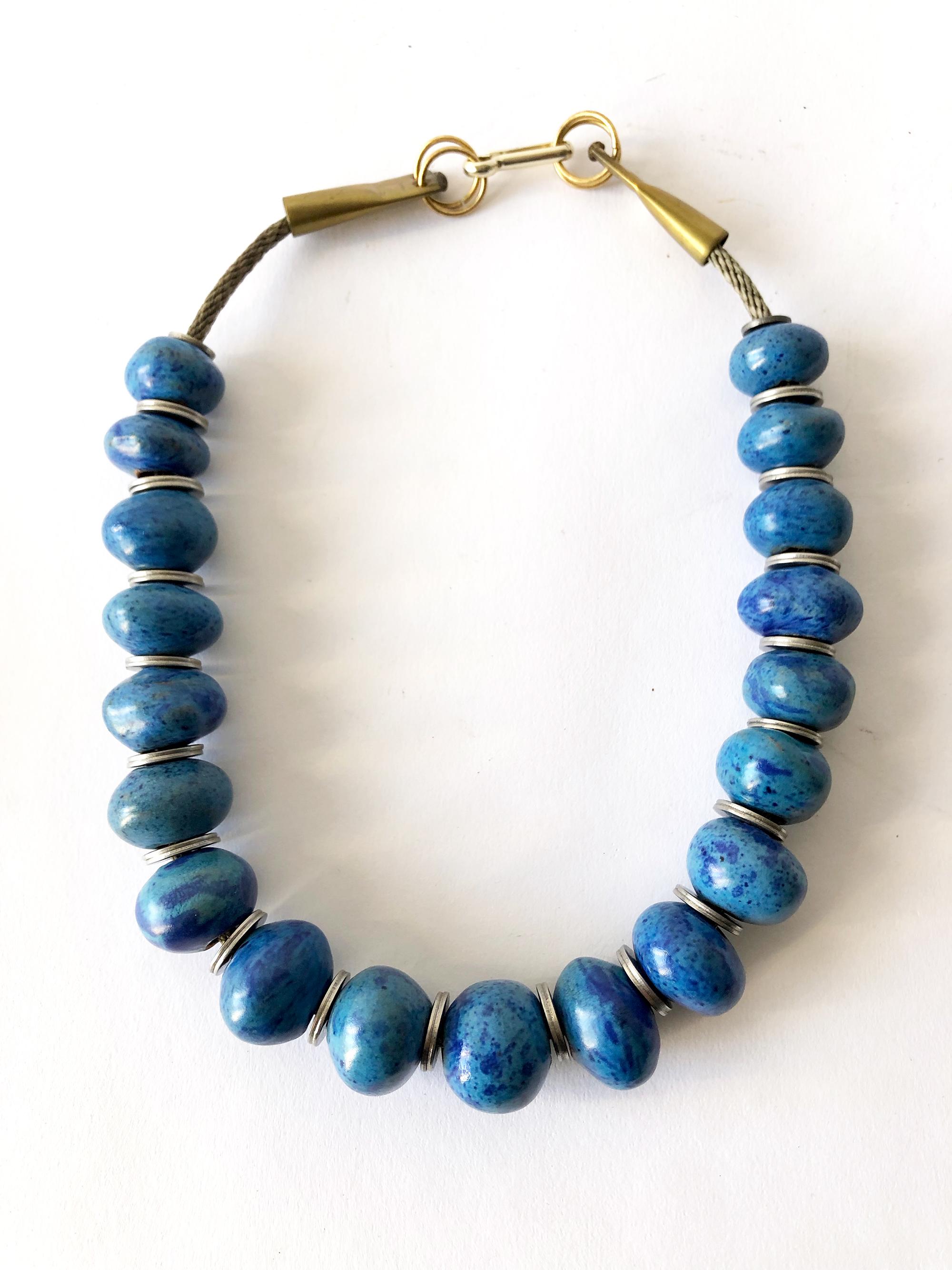 Handmade necklace of nineteen ovoid mottled turquoise beads separated by steel washers and strung on cable wire created by Doyle Lane of Los Angeles, California.  Necklace measures 22