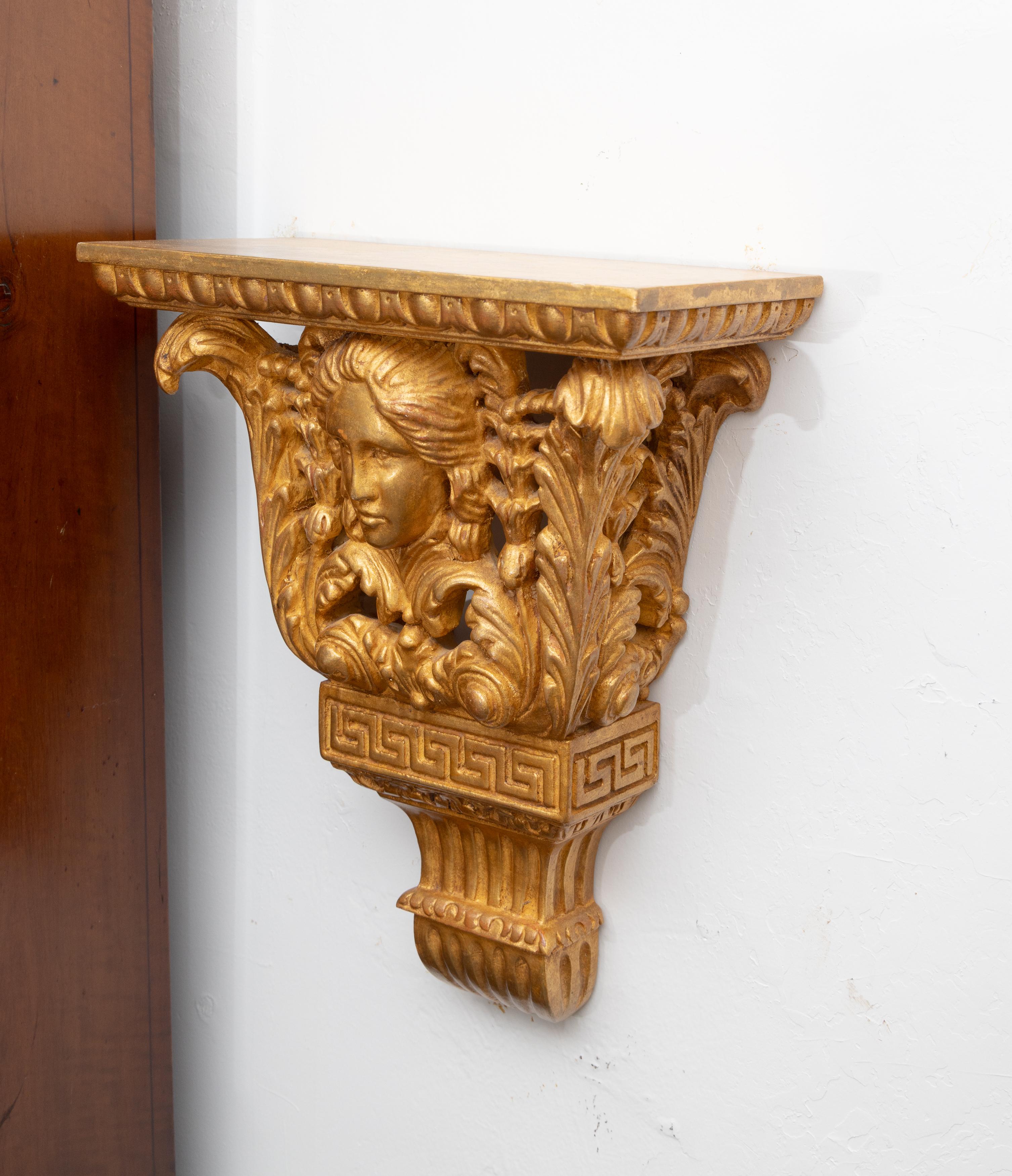 This is a stately pair of giltwood hand-carved wall brackets in the classical style, depicting a  female mask flanked by carved architectural features, 20th century.