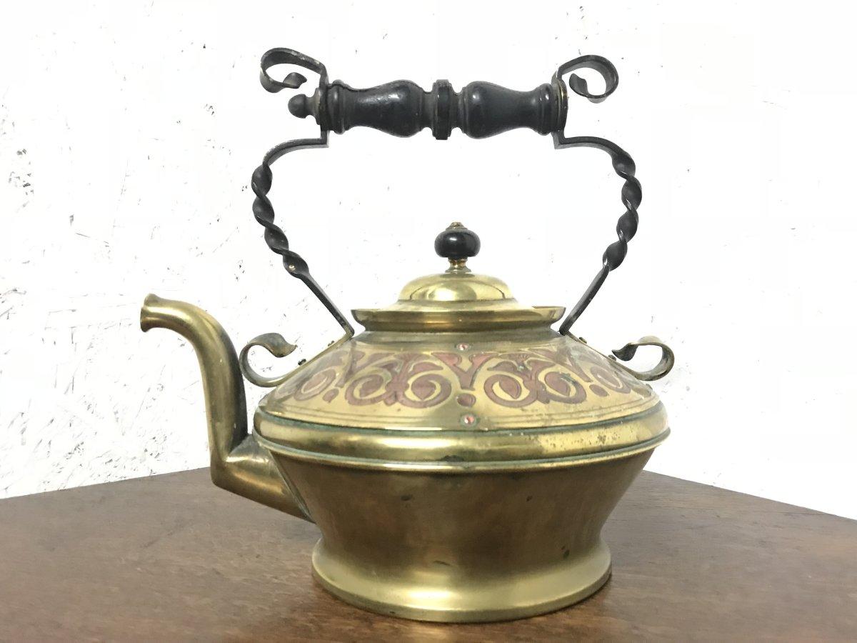 Dr C Dresser for Benham & Froud. A rare brass and copper teapot with stylised floral decoration with scroll and twisted supports to the ebonised handle, typical spout form, on circular base.
Stamped 'Pat 6886'.