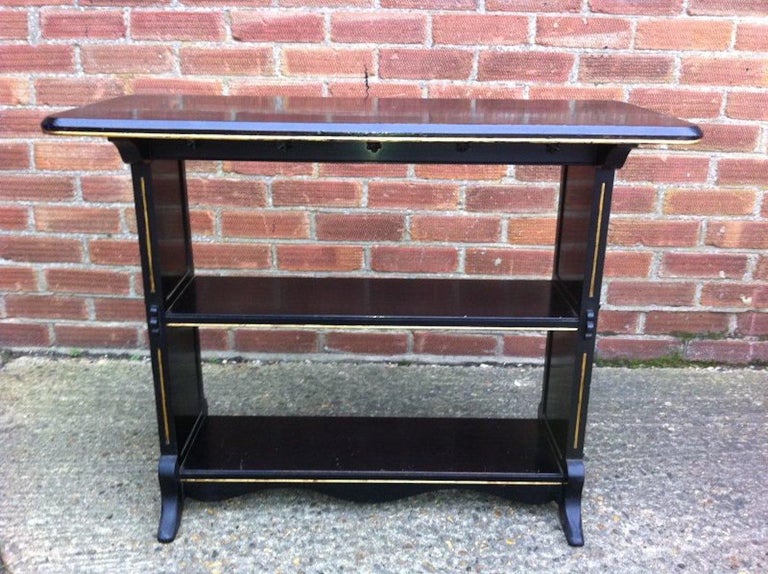 Dr C. Dresser, in the style of.
An Aesthetic Movement three-tier ebonized and incised parcel gilt oblong library or side table. With gilded line detail to the edge of the top, stylized carved star details to the apron below and through tenon and