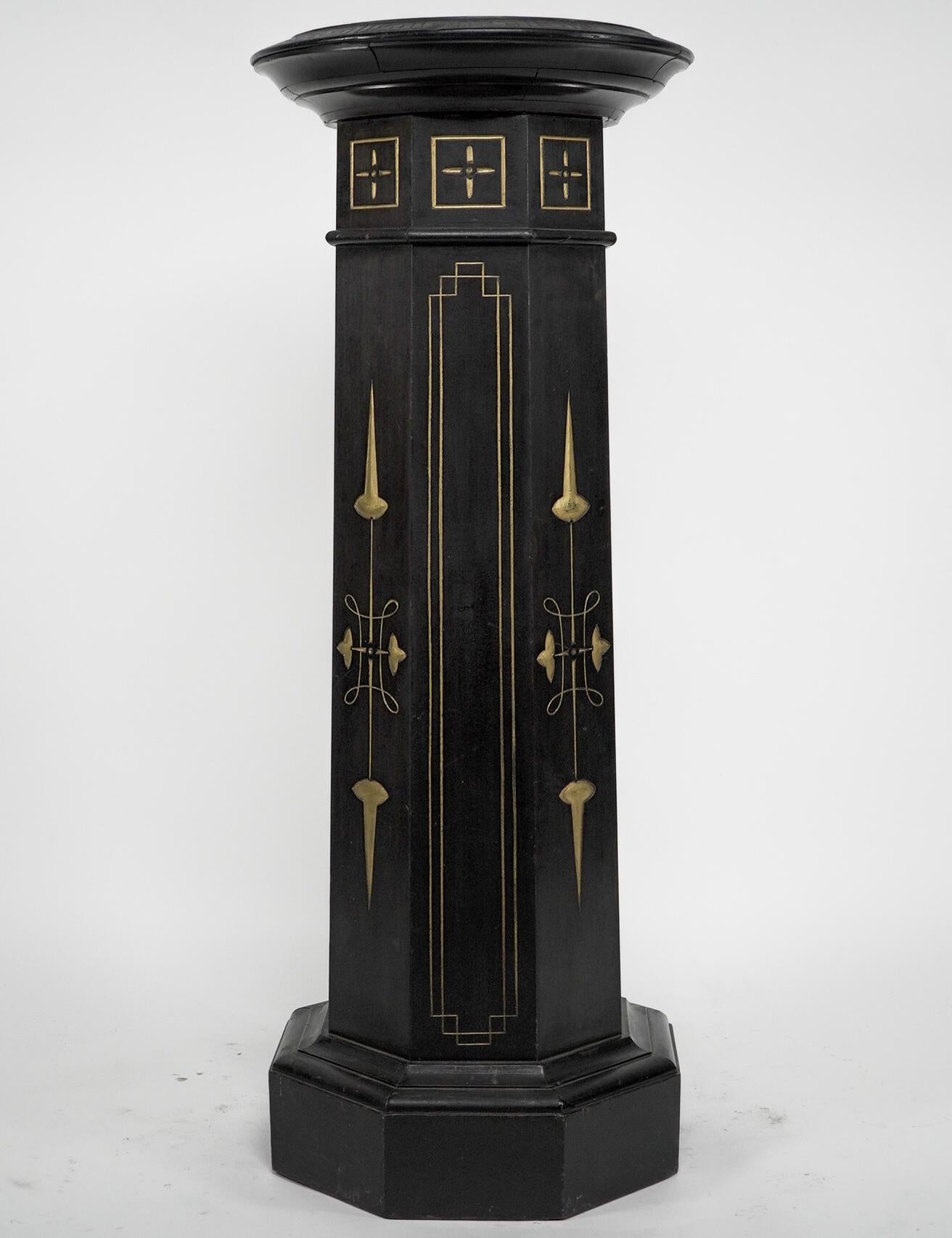 An Aesthetic Movement ebonized and gilded pedestal torchère in the style of Dr C Dresser. The circular top has a Greek key pattern band, the main octagonal column has incised and gilded decoration, on a plinth base. Dimensions - 38