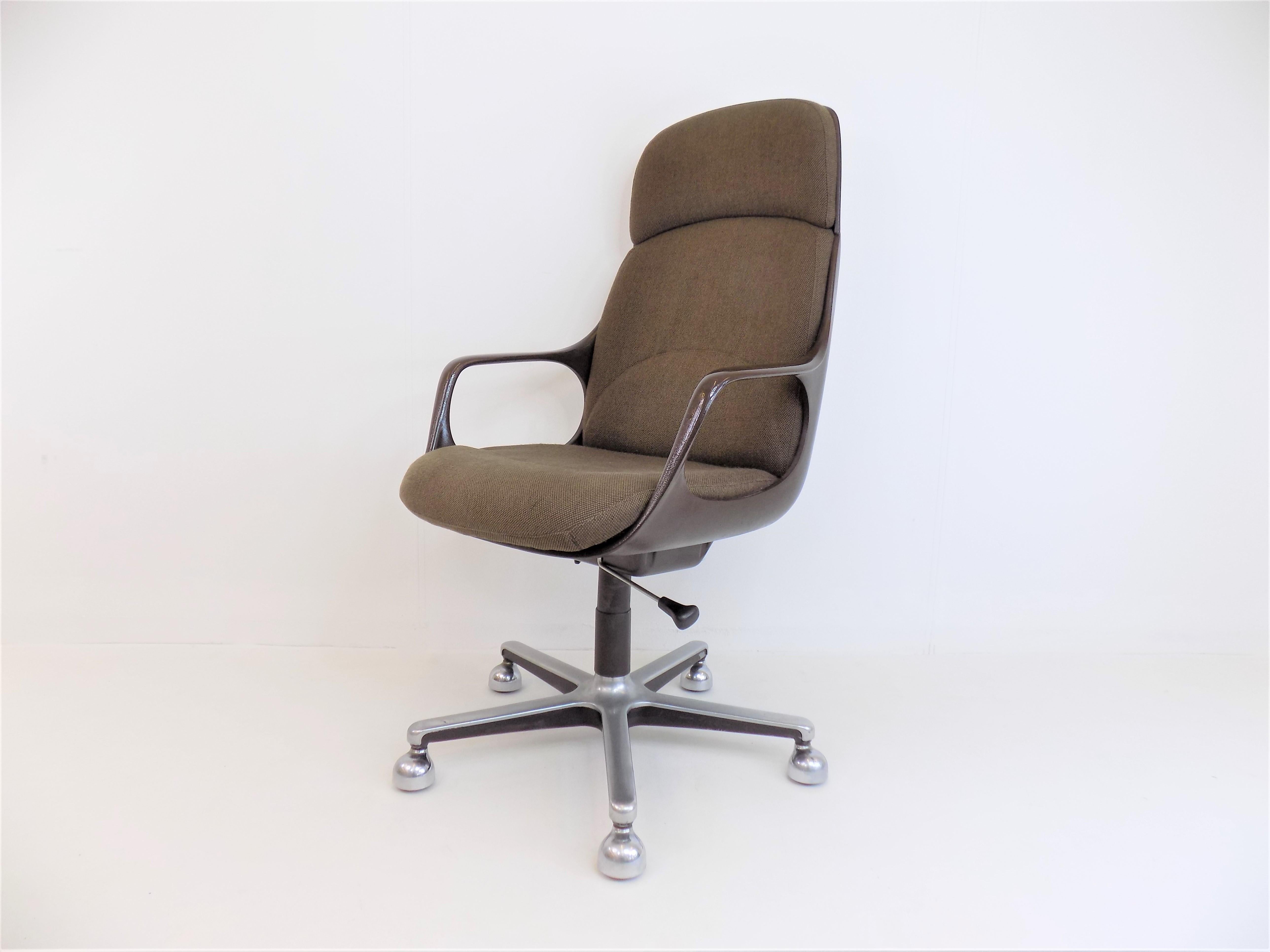 This Drabert office chair from the 1980s, still influenced by the Space Age, is in very good condition. The brown fabric upholstery of the seat and back cushions is immaculate. The backrest and armrests are made of a brown plastic shell and give the