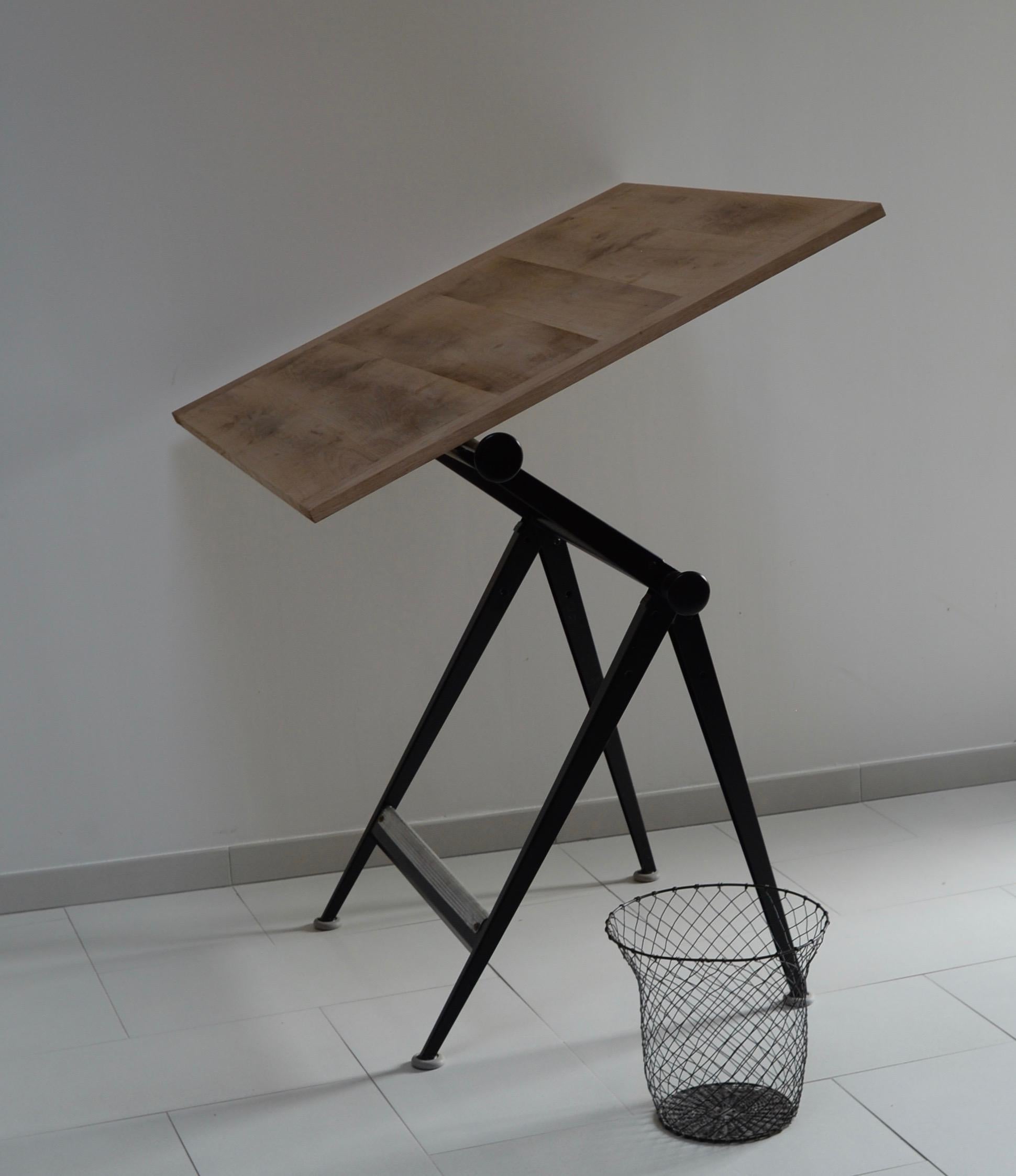 Drawing table reply by Friso Kramer and Wim Rietveld. The table has a dark metal frame and a wooden tray. This table was produced in 1965 by Ahrend de Cirkel. The 