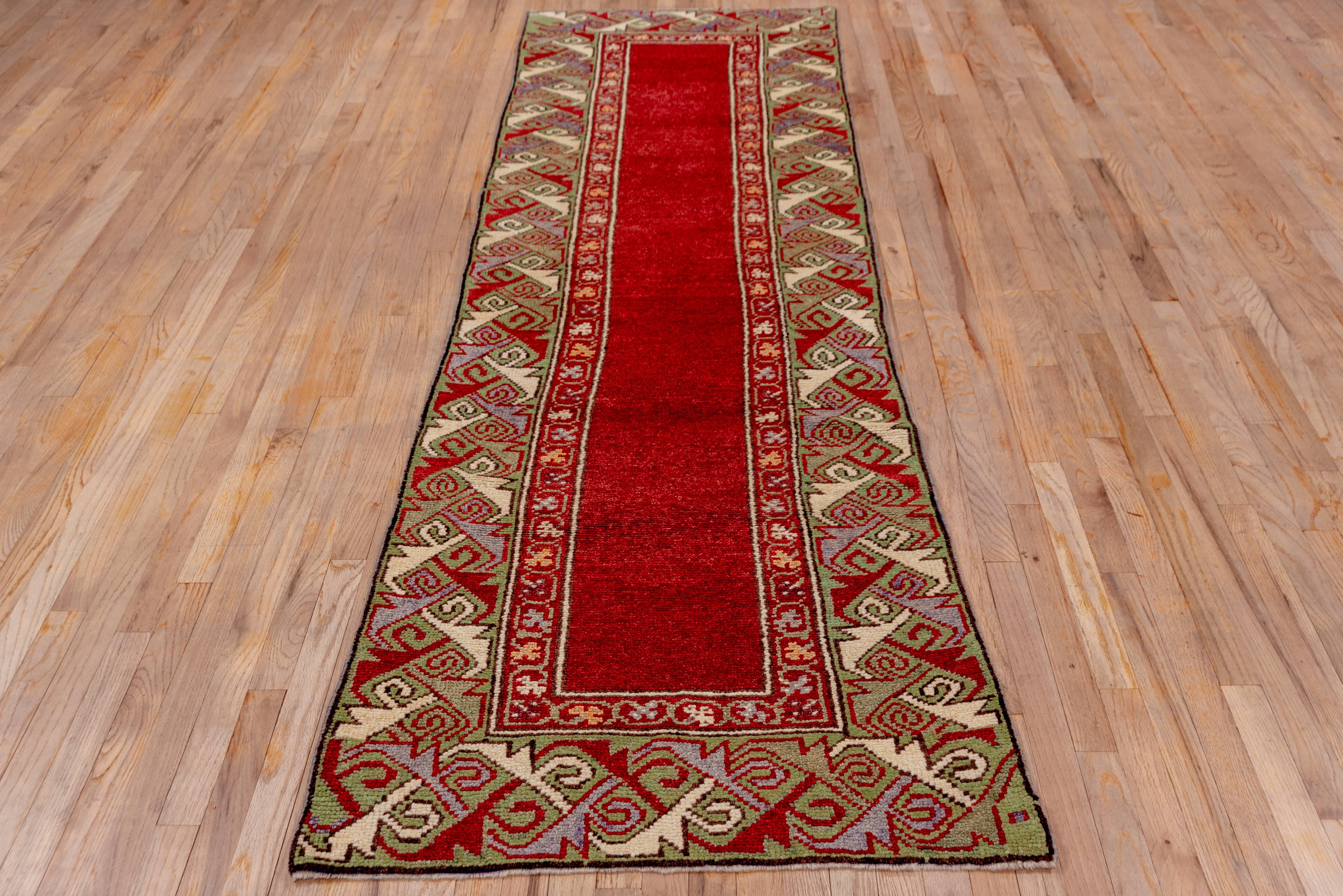 This extremely high pule, top condition eastern Anatolian runner has a plain mid-red field framed by a broad camel dragon border in the Caucasian style. Also Caucasian is the red inner border with a three leaf clover Meander. The ivory in the border
