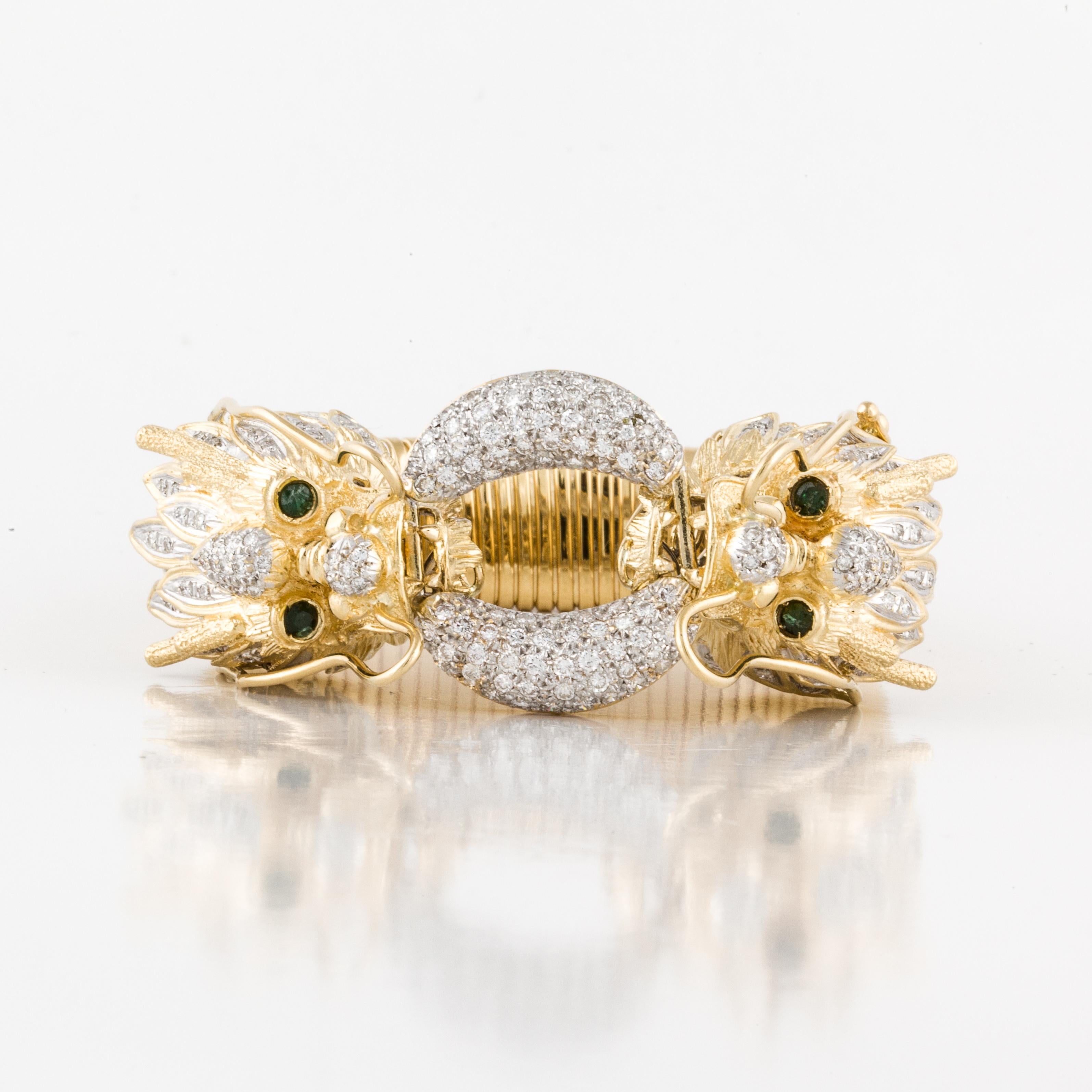 This bracelet is 18K yellow gold featuring two dragon heads facing each other.  There are a total of 224 round diamonds totaling 3.65 carats; G-I color and VS clarity.  There are also four round emeralds representing the eyes.  The bracelet measures