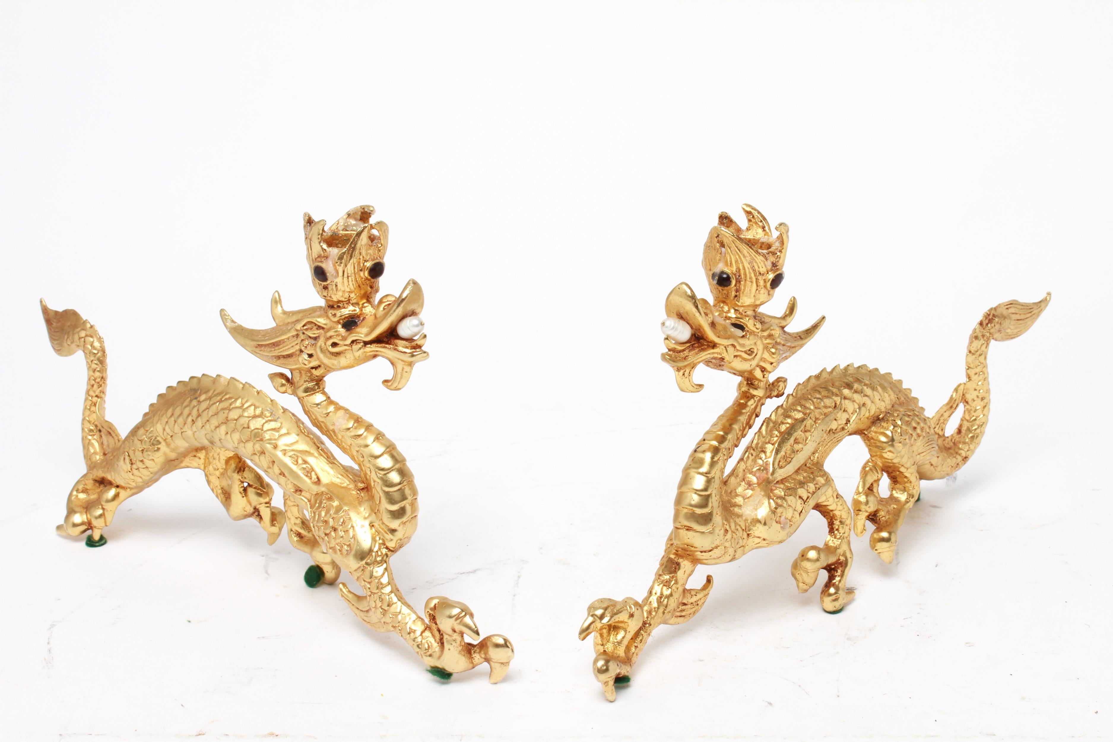 Asian Style pair of candleholders in gilt metal in the shape of dragons, with onyx eyes and pearls in their mouth, the candleholder having garnet inserts. The pair is in great vintage condition with age-appropriate wear.