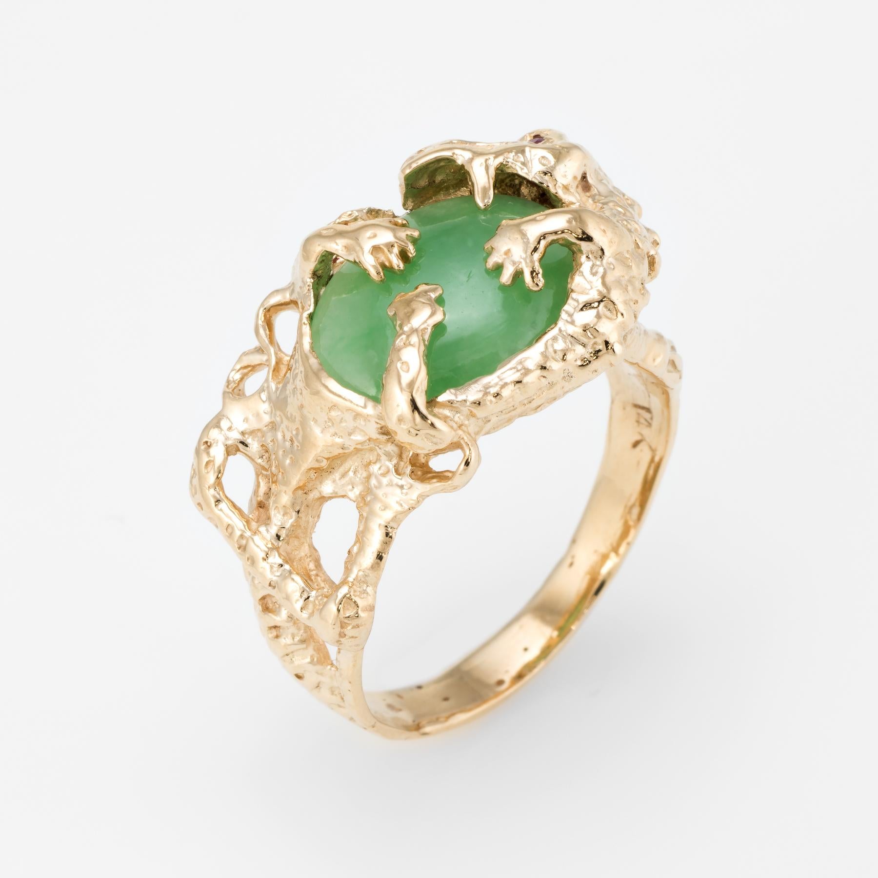 Finely detailed vintage cocktail ring, crafted in 14 karat yellow gold. 

Centrally mounted cabochon cut jade measures 13mm x 10mm (estimated at 7 carats). One approx. 0.02 carat garnet is set into the eye. The jade is in excellent condition and
