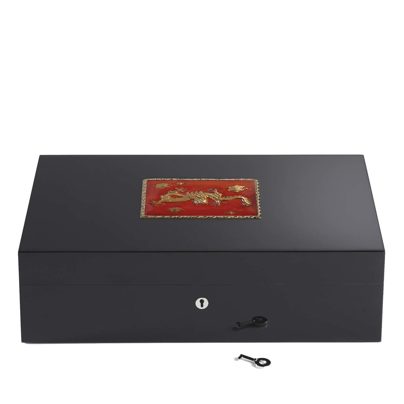 Exuding a precious and exotic allure, this humidor has an elegant wooden structure entirely painted black, that contains up to 110 cigars. The square decoration on the lid boasts a red background and depicts a golden camel. The decoration's edges