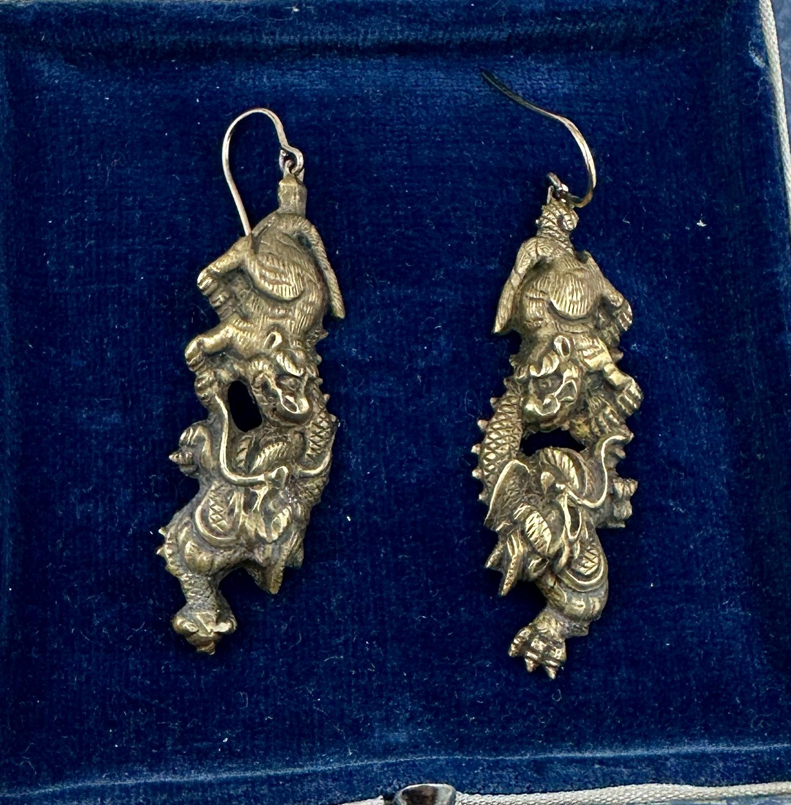 This is a very rare pair of Antique Shakudo Earrings from Japan depicting a Foo Dog or Dragon battling a Dragon.  The extraordinary imagery is full of history, drama and mystique.  The Dragons and Foo Dogs are absolutely wonderful with superb