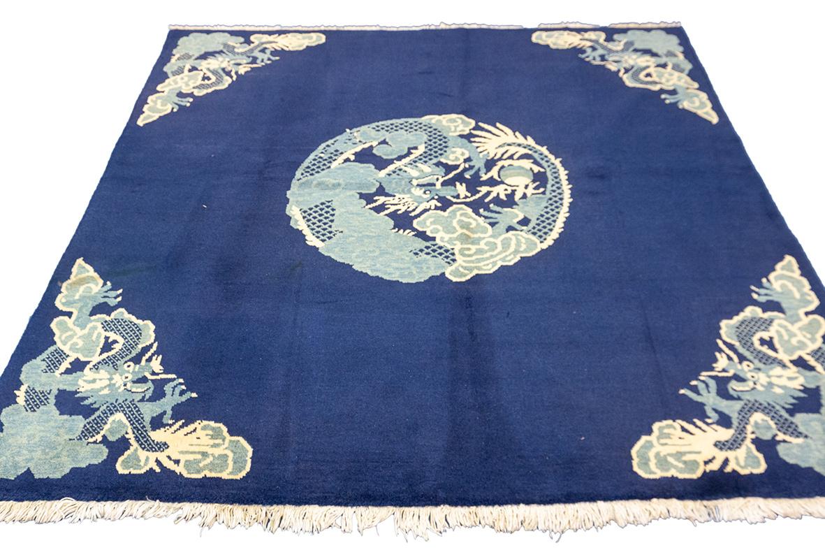 Ce tapis Dragon de Chine, mesurant 188 x 190 cm, respire l'élégance traditionnelle orientale grâce à son design saisissant. Le fond bleu marine offre un contraste saisissant avec les tons bleu pâle et ivoire du motif central du dragon, qui symbolise