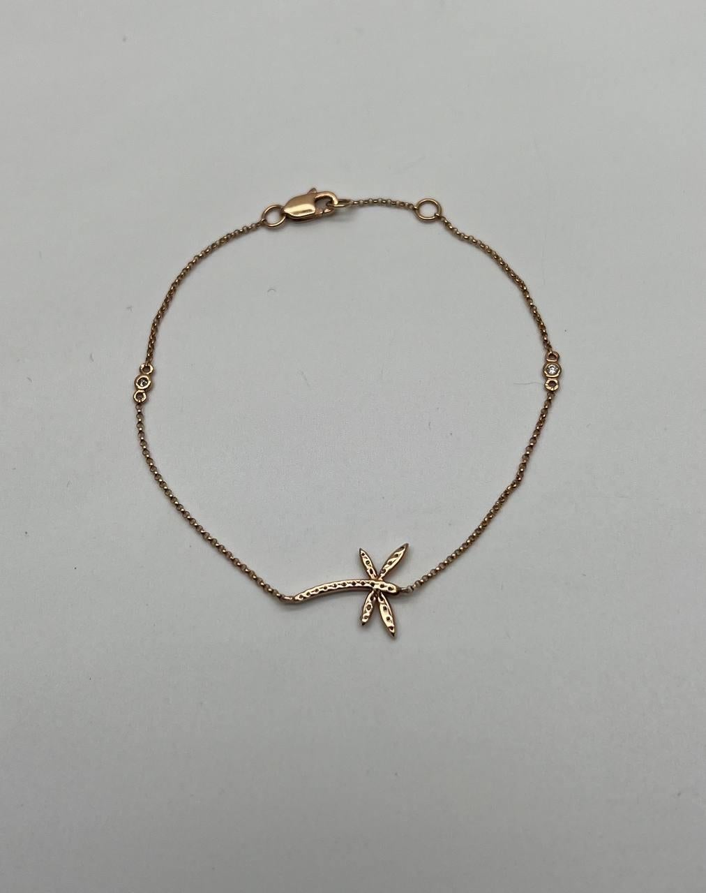 Cet élégant bracelet présente une chaîne délicate en or rose 14k. La pièce maîtresse est un motif de libellule orné de diamants blancs, totalisant 0,12 carats. Les diamants sont sertis de manière à rehausser leur éclat par rapport à la teinte chaude
