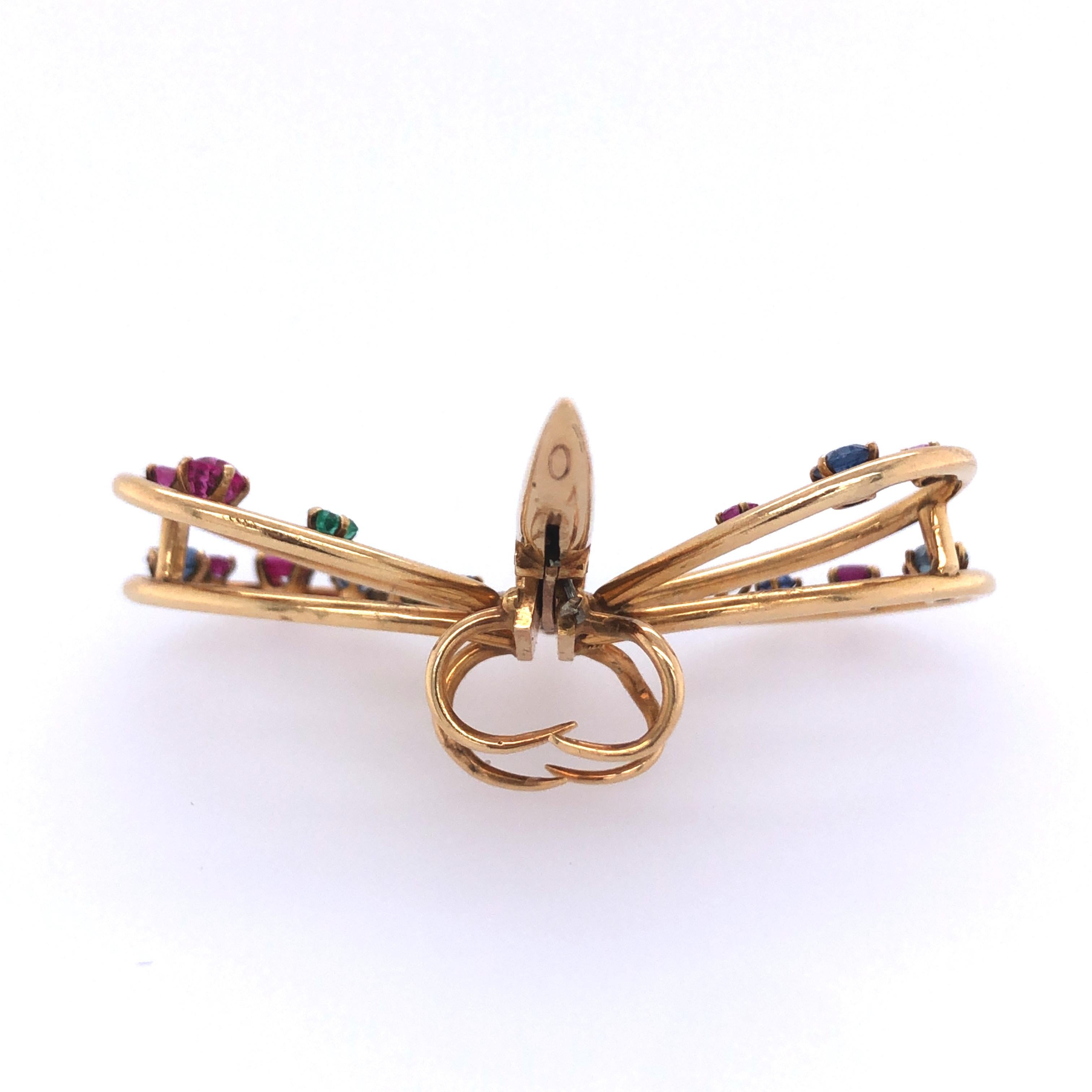 A stylized gold dragonfly with wings of circular or square-cut rubies, sapphires, and emeralds
Yellow gold 1 ¾ x 2 ins; Gross weight 14.6 9.3 dwts 