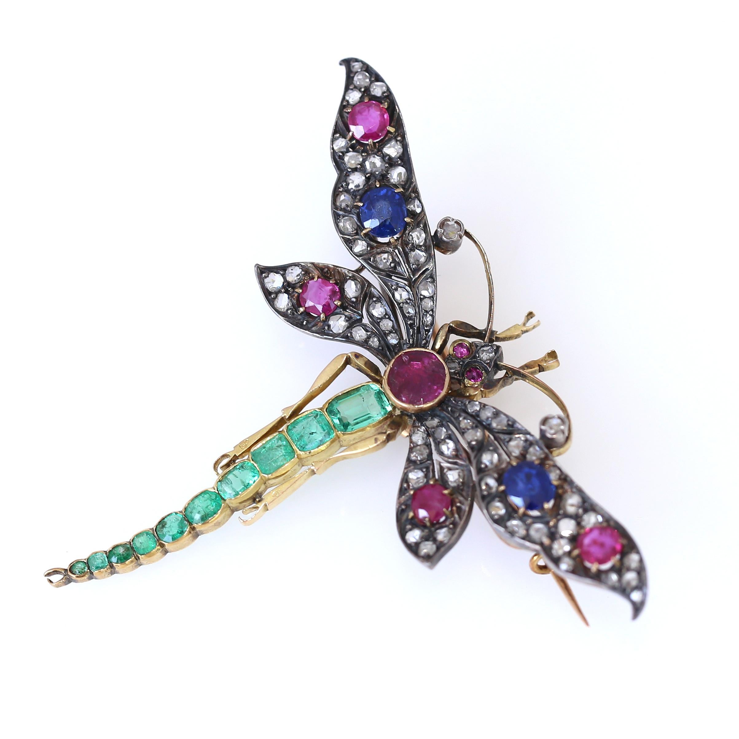 Huge Dragonfly Brooch (pin) comprising of fine Emeralds degrading in size from the body to the tail. Five Oval shaped Rubies and Sapphires have decorated the wings with old-cut Diamonds. Marvelous design and execution. 
Victorian Period Style was