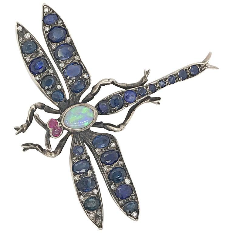 Beautiful antique dragonfly pin crafted from 14kt white gold and sterling silver. 
Oval and round Sapphires combine for approximately 4.00 carats 
36 Antique Rose Cut Diamonds total approximately .50 carats 
Rubies in the eyes total aproximately .10
