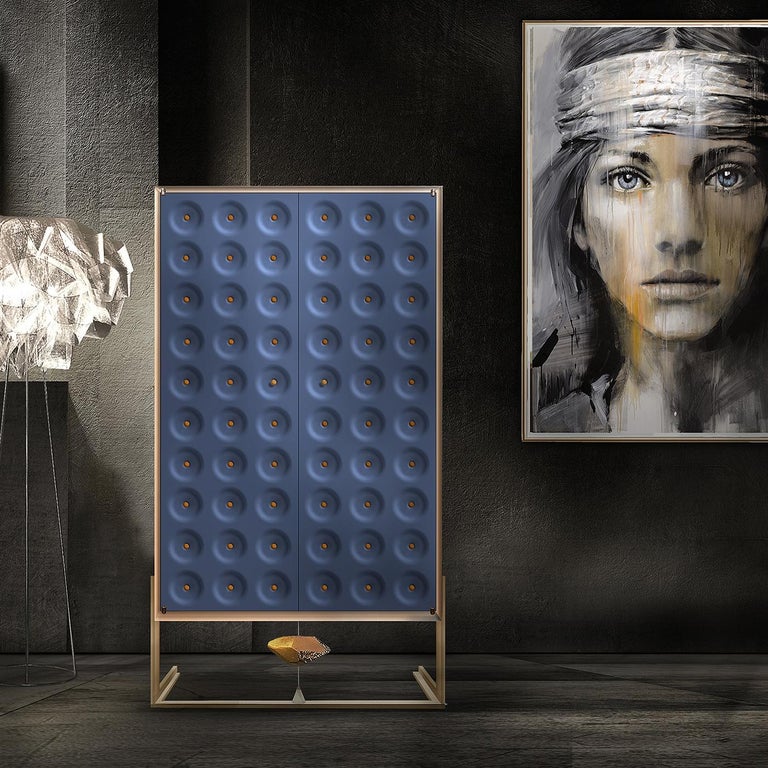 An elegant and charming design characterizes the Drake Cabinet, designed by Giuliano Cappelletti. Supported by a bronze sculpture by the artist Kyoji Nagatani, the 160 cm tall unit features inner shelves with a drawer and patterned doors in blue