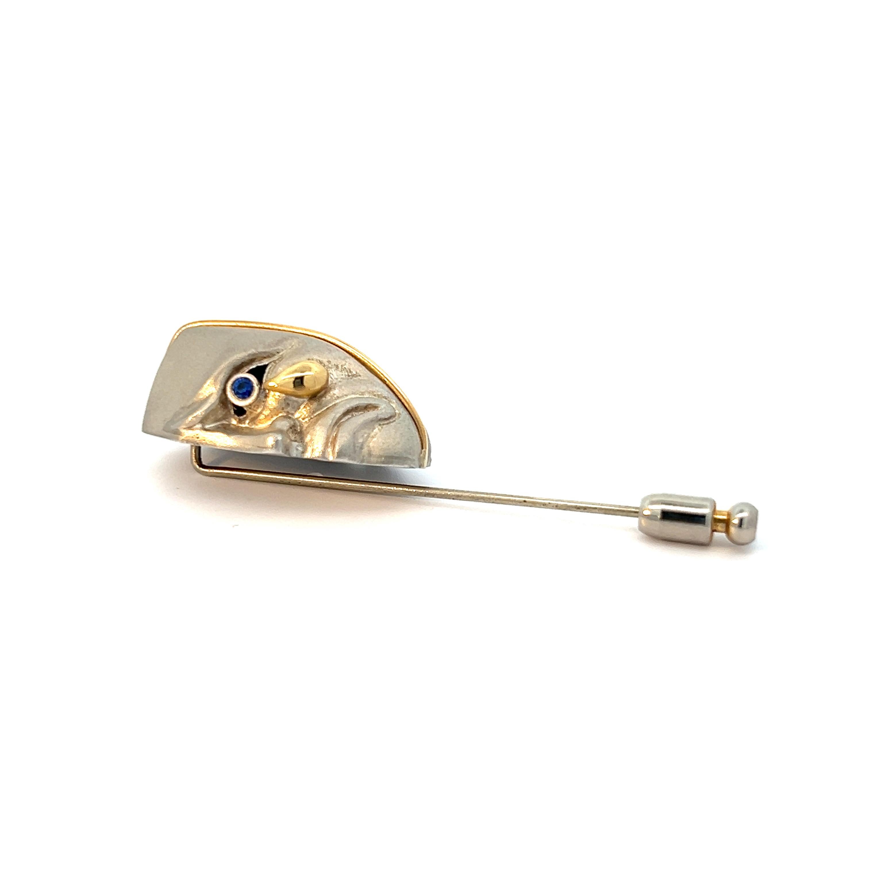 In the heart of this intricately crafted stick pin lies a captivating tale of both joy and sorrow, spun into the very essence of its design. Fashioned from the noble metals of sterling silver and 18k yellow gold, this piece embodies a striking