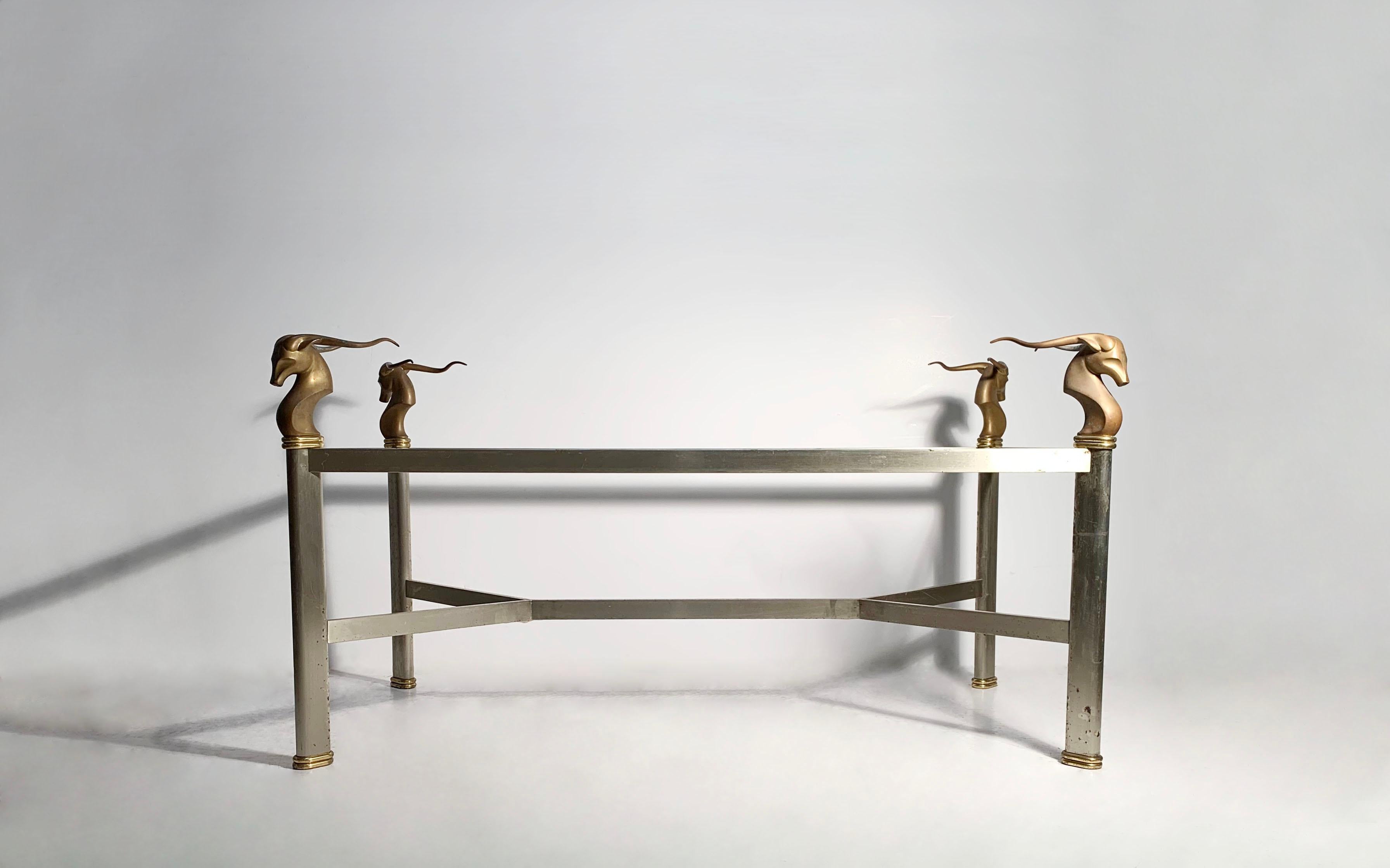 A Dramatic Table base seeing as either a Dining Table, Buffet Table, or Desk. Dating to the 1970s to possibly the 1980s.

Mounted at each corner are Solid Heavy Bronze Antelope heads which support a glass or top. Uncertain to the origin. Possibly