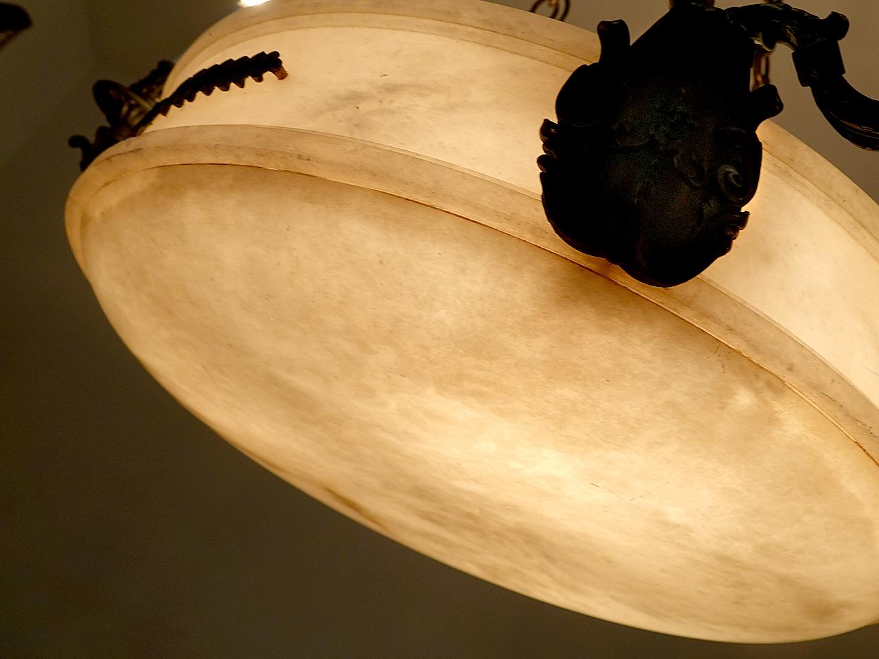 Il s'agit d'un lustre à vasque en albâtre très impressionnant et élégant. Ce bol de 24 pouces de diamètre, sculpté à la main, a une forme unique, un fond arqué et des côtés hauts et plats. Trois doubles candélabres en bronze sont fixés à l'extérieur