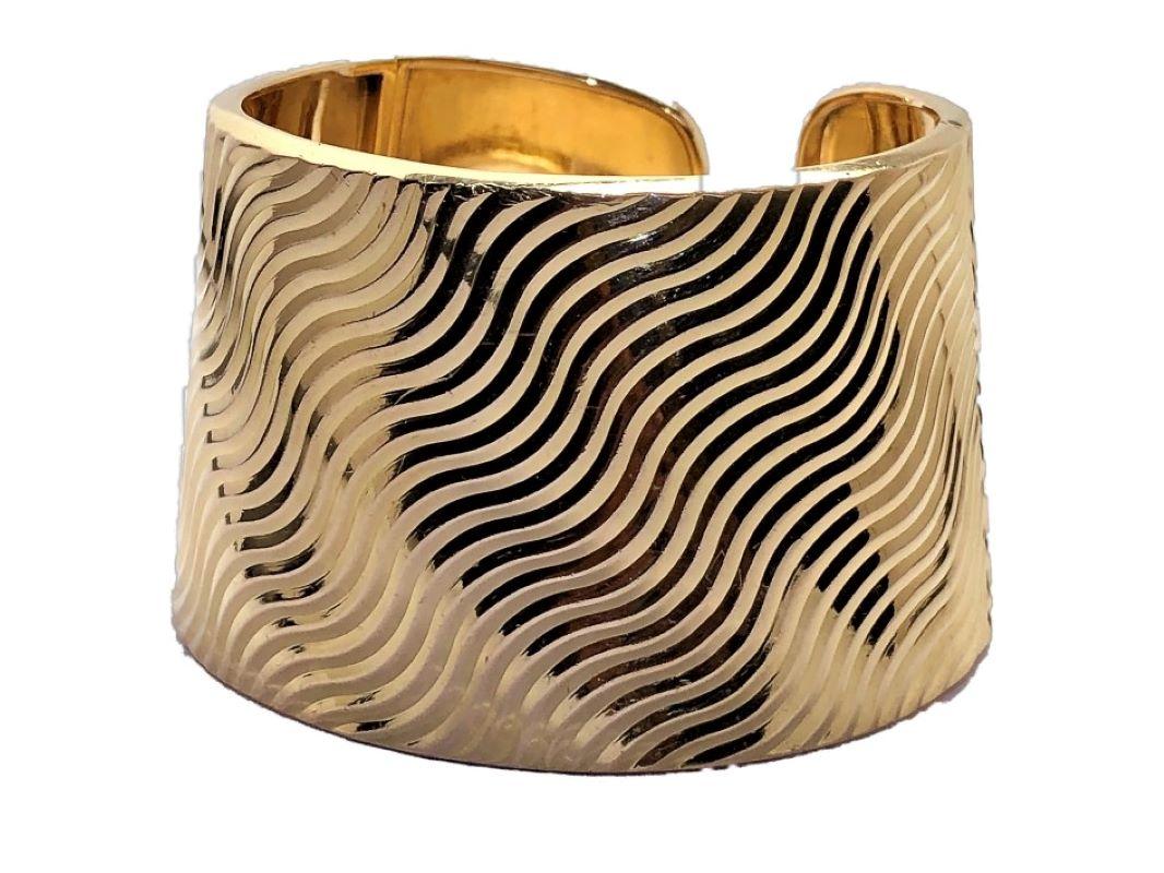This unusual 18k Yellow gold Italian cuff bracelet is finished over it's entire surface with a deep cut undulating diagonal pattern which makes it shimmer as light hits it from different angles. Measures a full 1 13/16 inched wide. Fits a medium to
