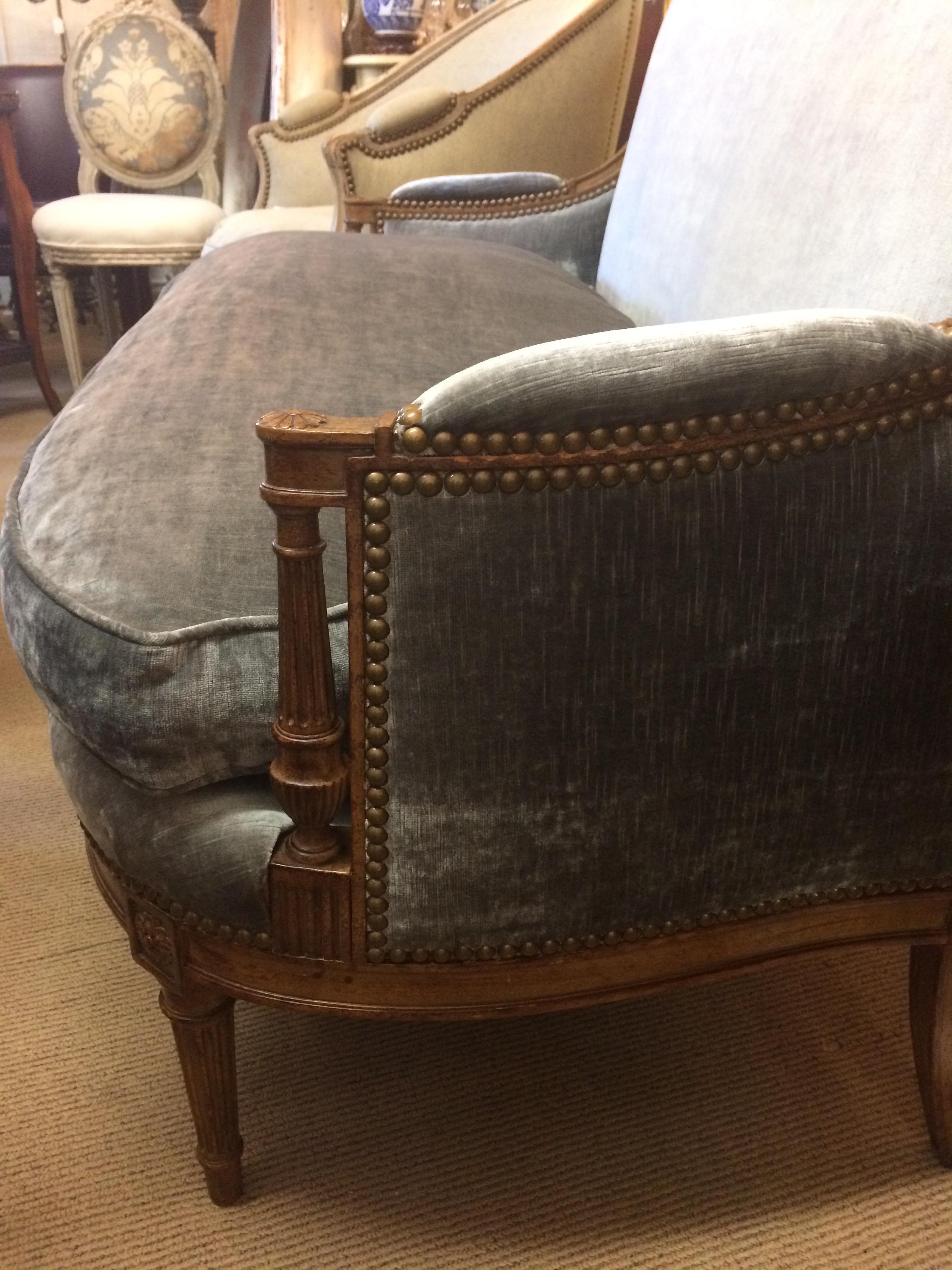 Antique French neoclassical style loveseat settee having beautiful carved walnut frame and new richly elegant platinum velvet with down cushion. Window pane back and nailhead details, circa 1910. Arm height 22 inches.