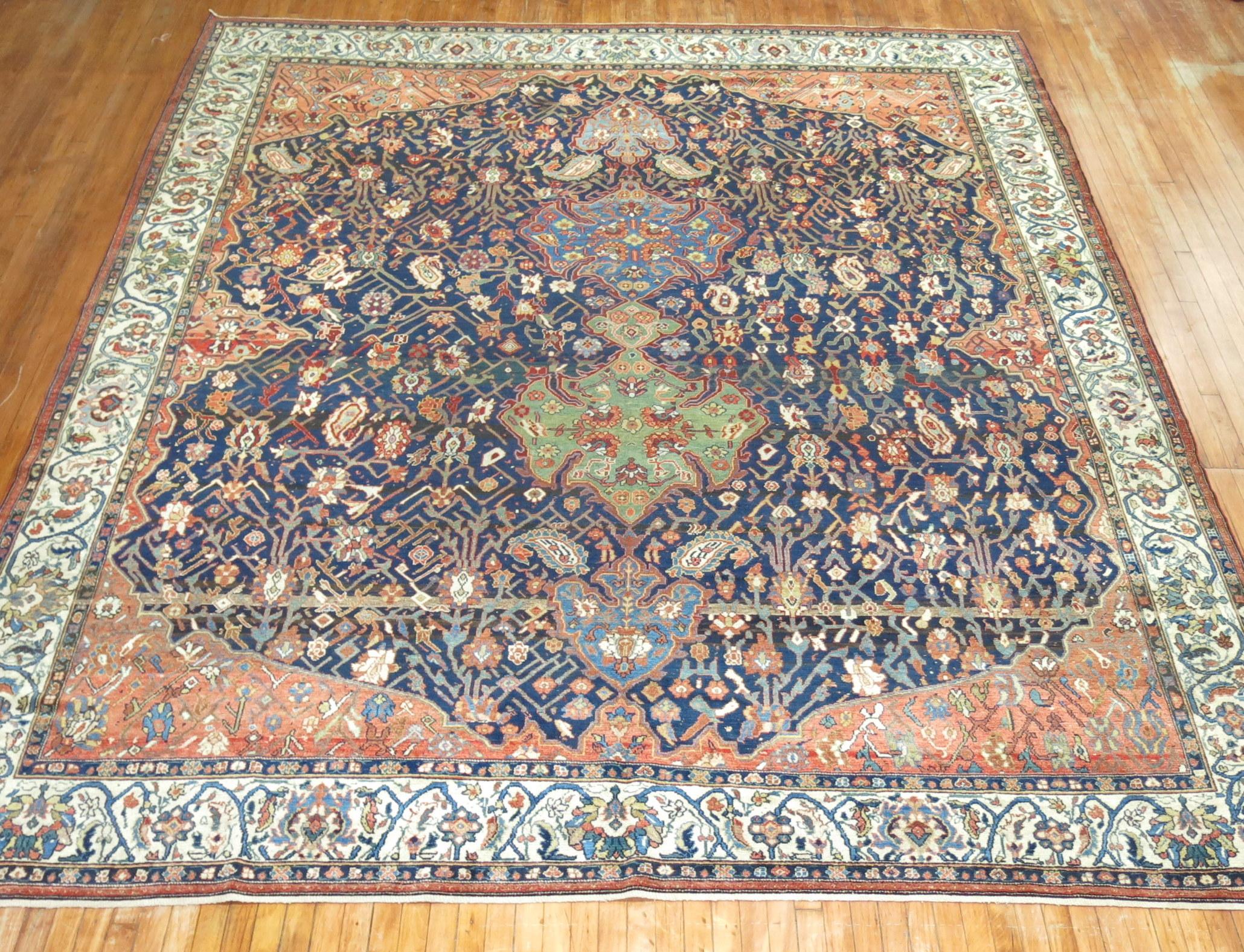 High Decorative early 20th-century Room size Persian Malayer rug with a dramatic pattern in rust, blues and green on a navy field surrounded by an ivory border

Measures: 10'8'' x 13'2''.