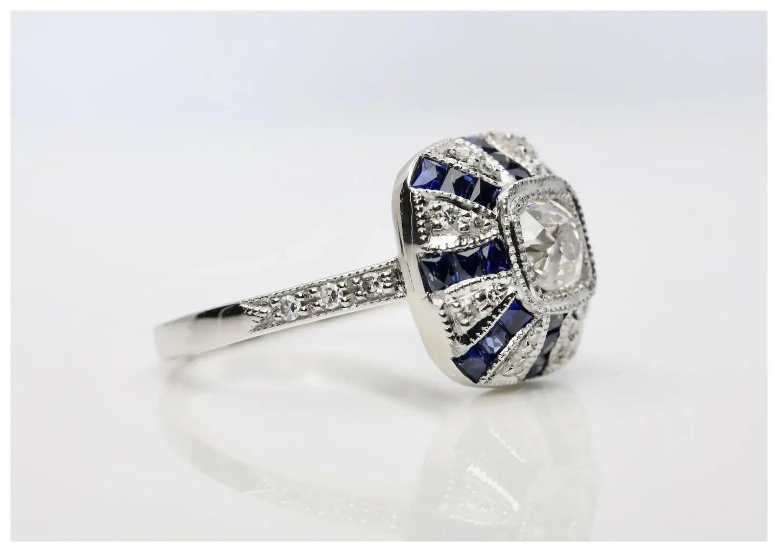 A beautiful and dramatic diamond, and French cut sapphire ring in platinum.

Centered by a 0.60 carat old mine cut cushion shaped diamond of H color, VS2 clarity set in a miligrained platinum bezel.

Framed by rays set with 24 French cut sapphires