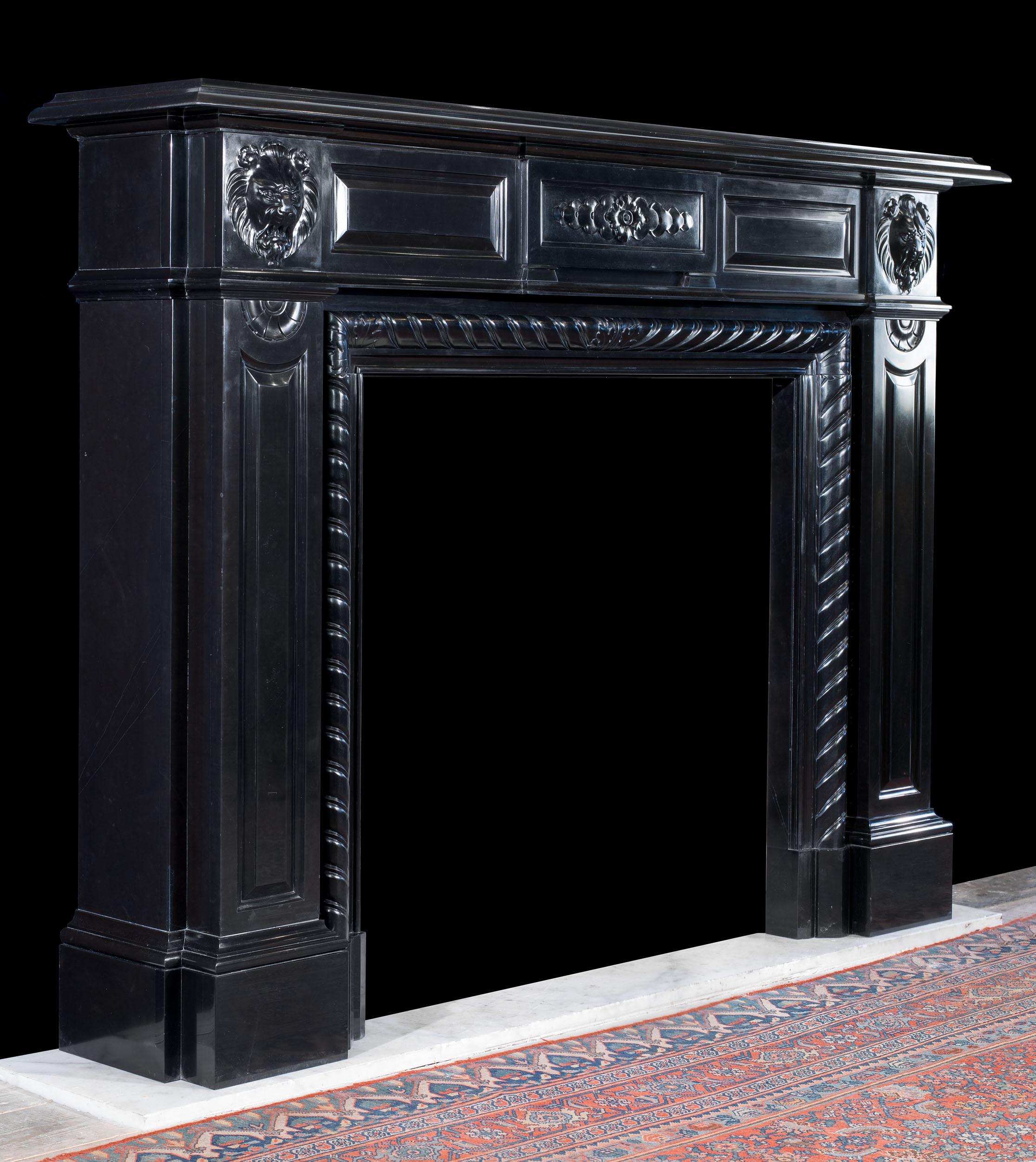 An imposing and striking large fireplace in highly polished Belgian Black Marble. The wide and deep moulded shelf sits above a panelled frieze with a crisply carved central tablet, which is flanked by two lion mask endblocks over wide panelled jambs