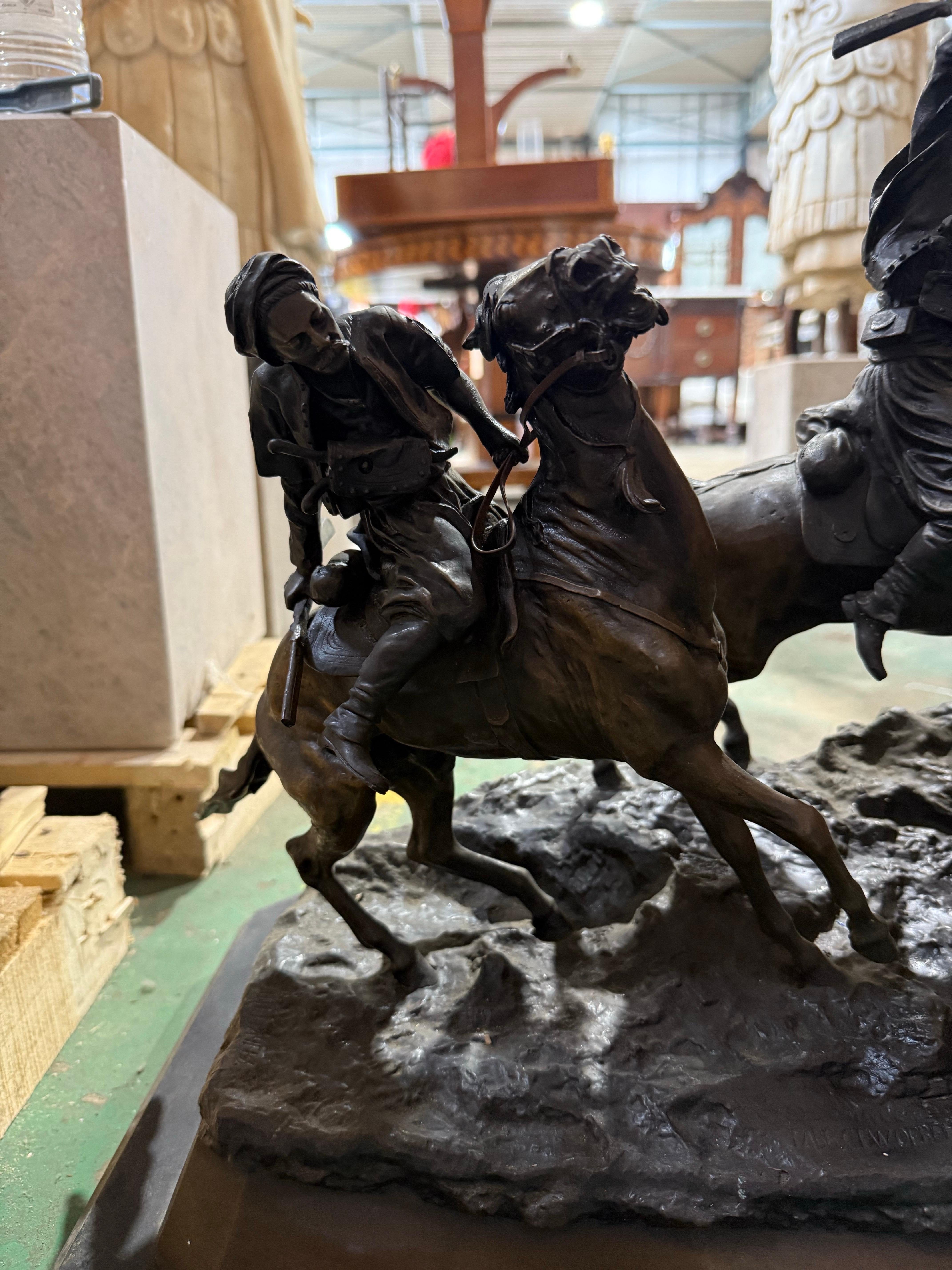 Una scultura in bronzo potente e intensamente dinamica che raffigura due guerrieri a cavallo impegnati in una battaglia, firmata Lanchay. I cavalieri, vestiti con abiti tradizionali orientali o nordafricani, vengono sorpresi a metà carica: uno