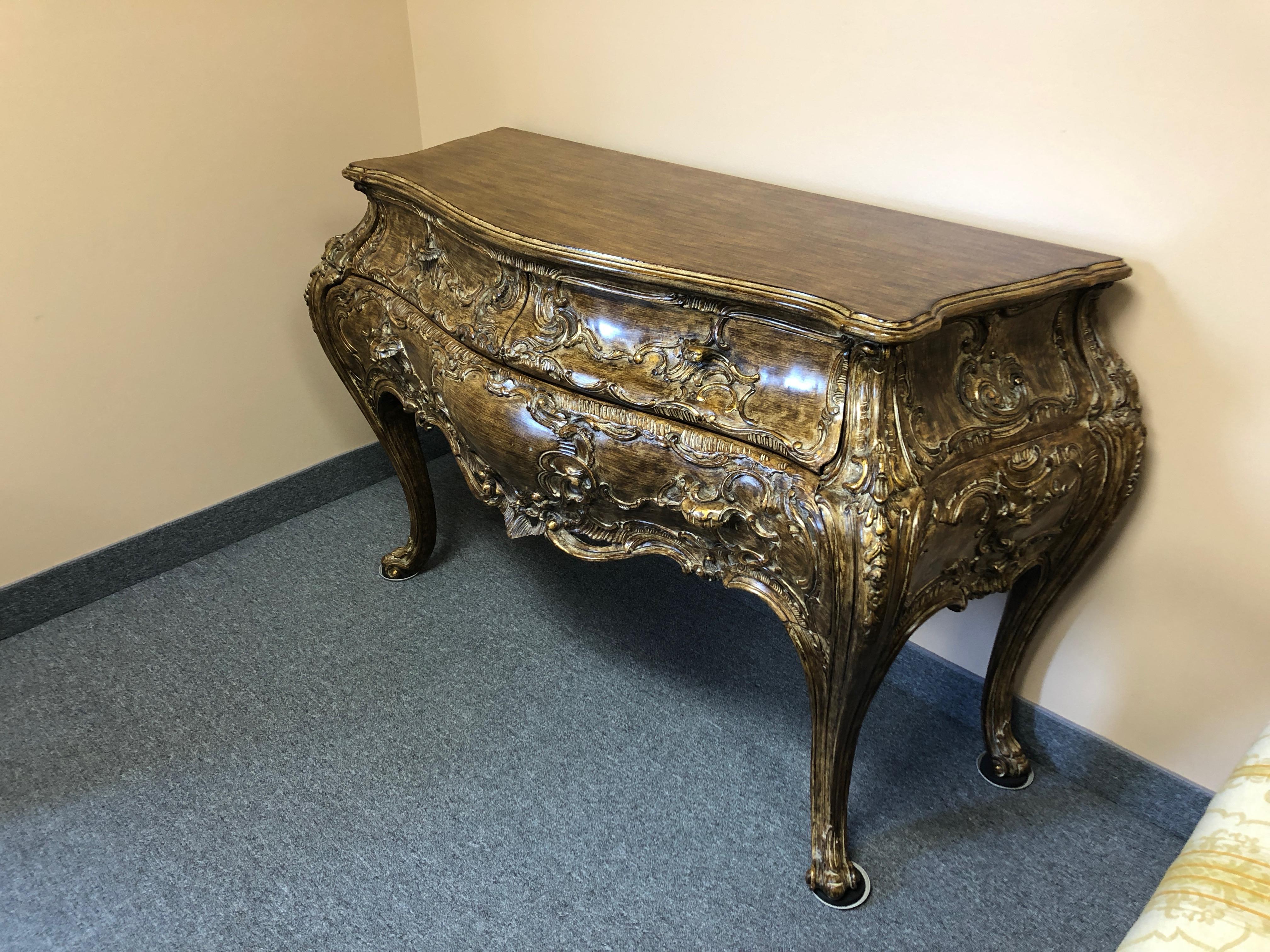 Very dramatic gilt finish ornately carved Rococo commode having handles that are sculpted parts of the drawer fascades. Curved cabriole legs and hand painted finish with two smaller drawers on top of one large drawer.
