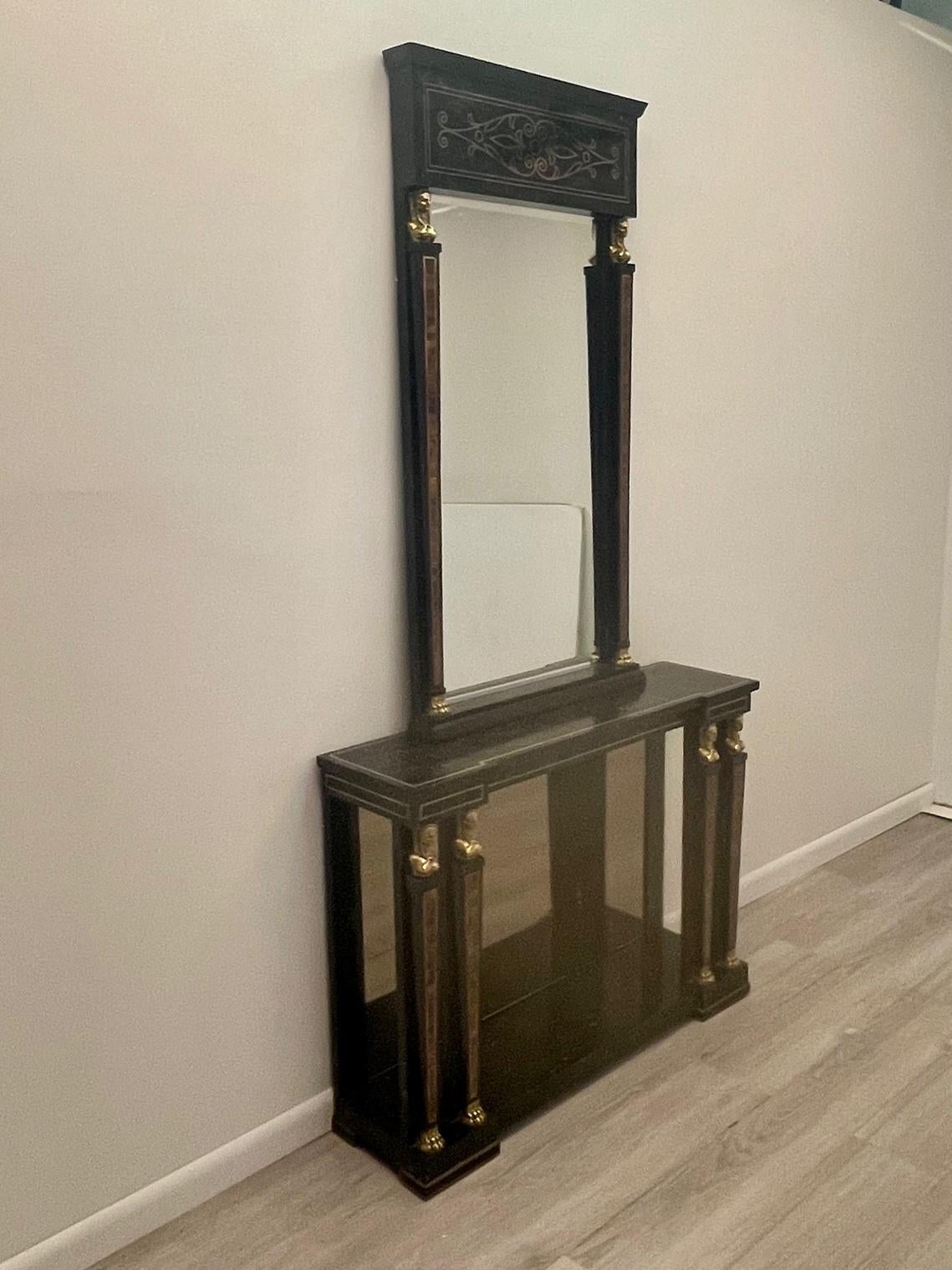 Glamorous Egyptian Revival style console and matching mirror made of black tessellated stone having detailed inlay decoration in brown as well as inlaid brass outlines. There are stunning brass figural mountings on the top of the columns that