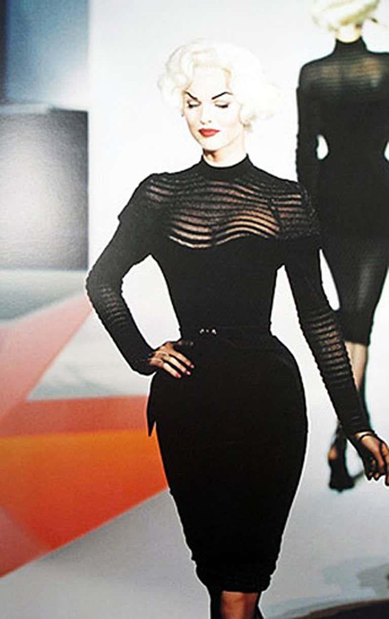 Dramatic Fall 1995 Thierry Mugler Black Velvet Structured Dress, Museum. Features transparent knit yoke, sleeves and hem. 
Corset style bodice with matching belt; Zipper at back with snap button closure at neckline. 
As seen in the book, 