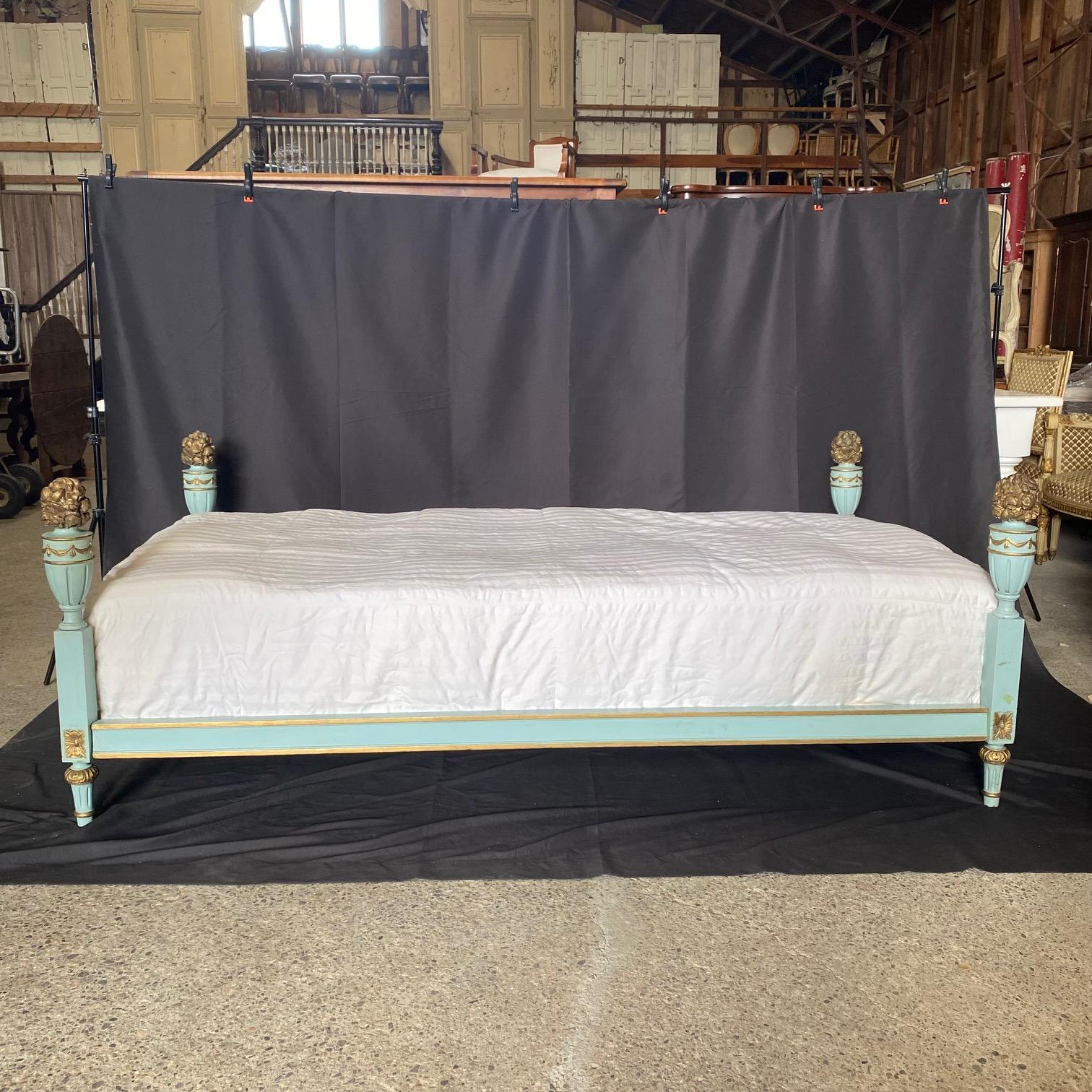 A French Louis XVI style painted wood daybed from the early 20th century with foliage carved decor and lovely eggshell blue paint with gold embellishments. The sides are meticulously carved, enhancing the daybed's exquisite silhouette. The creamy