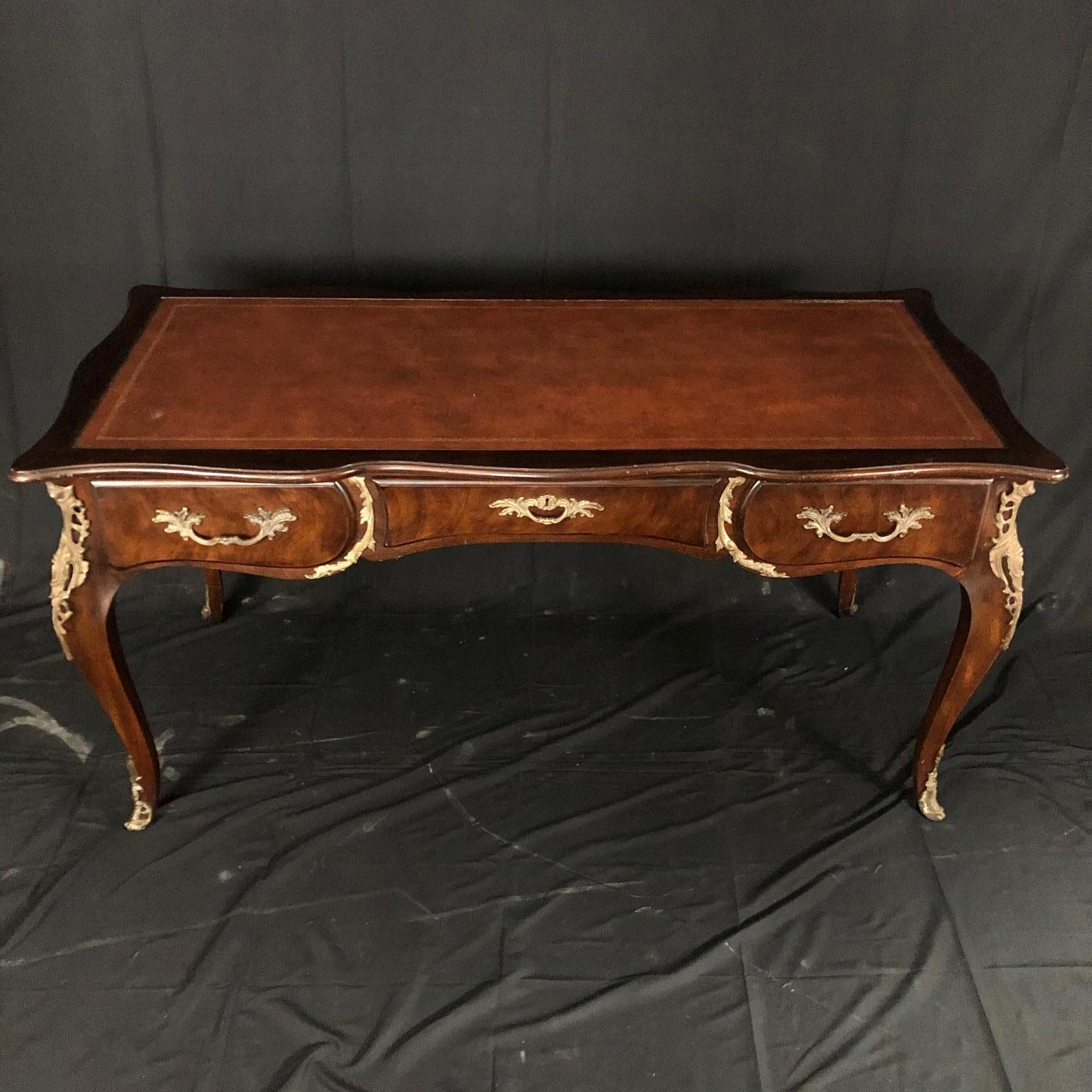 French Louis XV style walnut bureau plat desk raised on elegant cabriole legs with ormolu wraparound sabot. The 3 drawers are decorated with gilt bronze handles and the back is also adorned with gilt bronze so the desk would command the attention it