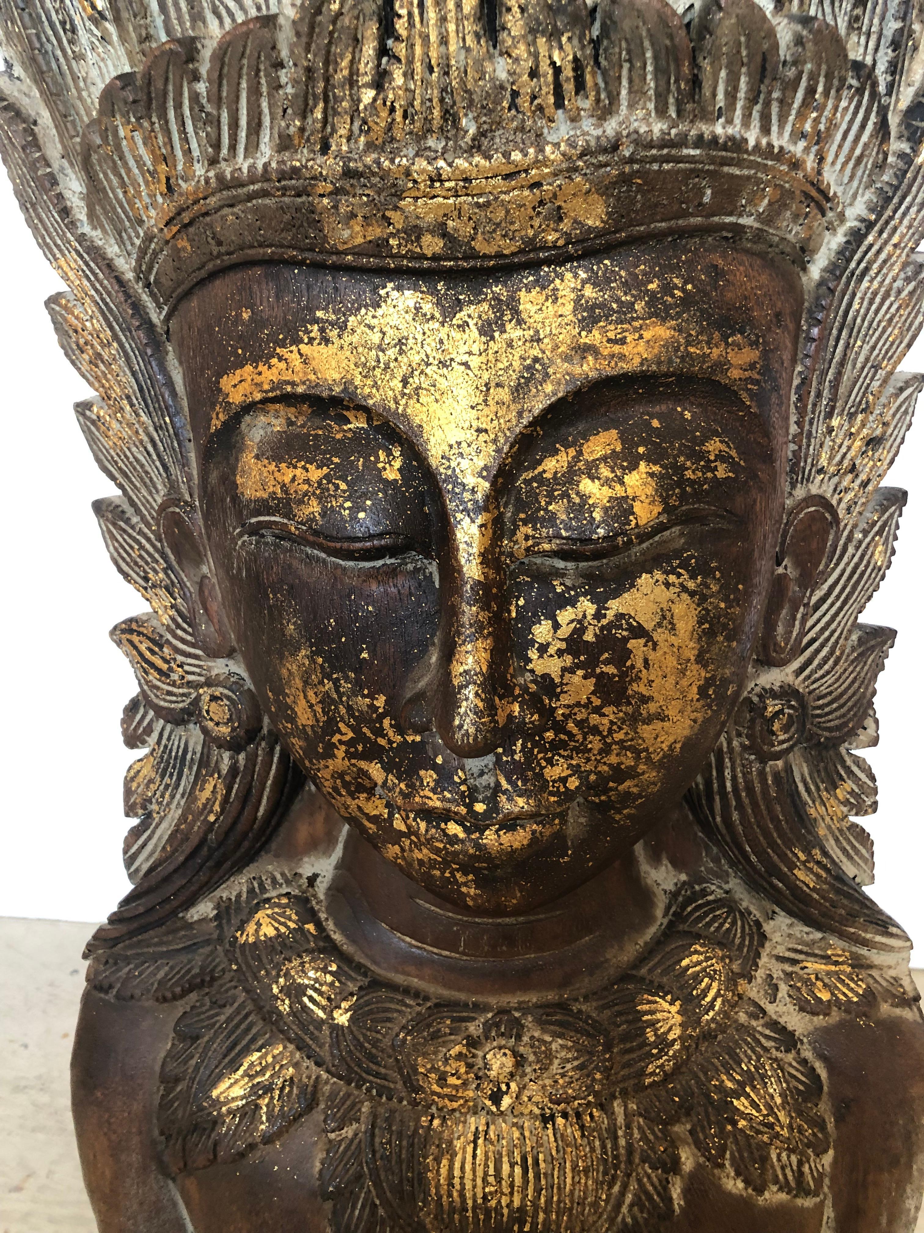 Dramatic and impressively large carved and  gilded wooden sculpture of a Thai female bust having ornate head dress.  Incredibly carved from one solid log of wood and mounted on a simple black wooden base with two iron rods. 